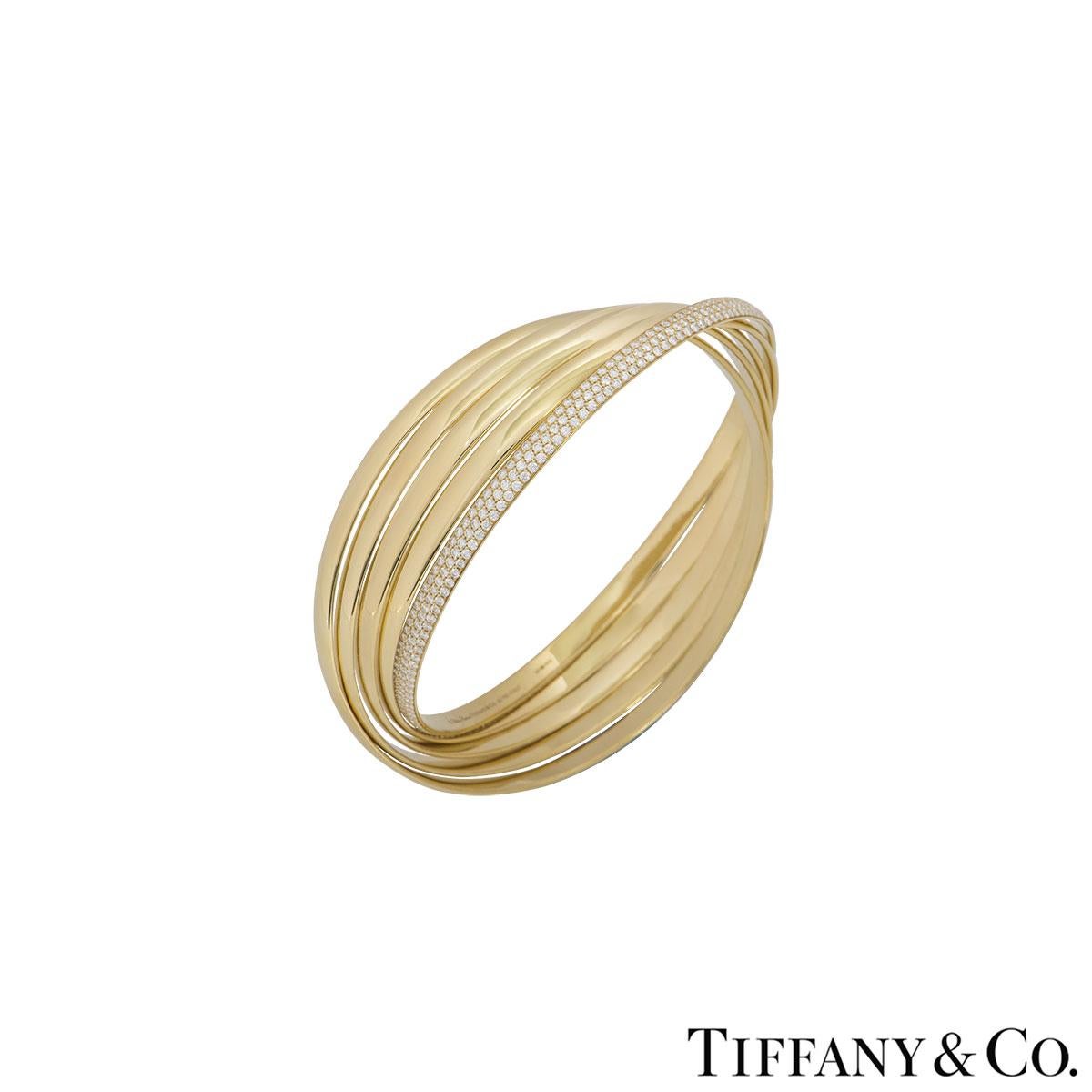An 18k yellow gold diamond 5 band Paloma's Melody bangle by Tiffany & Co. from the Paloma Picasso collection. The bangle features 5 overlapping yellow gold bands with 1 set with round brilliant cut diamonds in a pave setting with a weight of 2.69ct.
