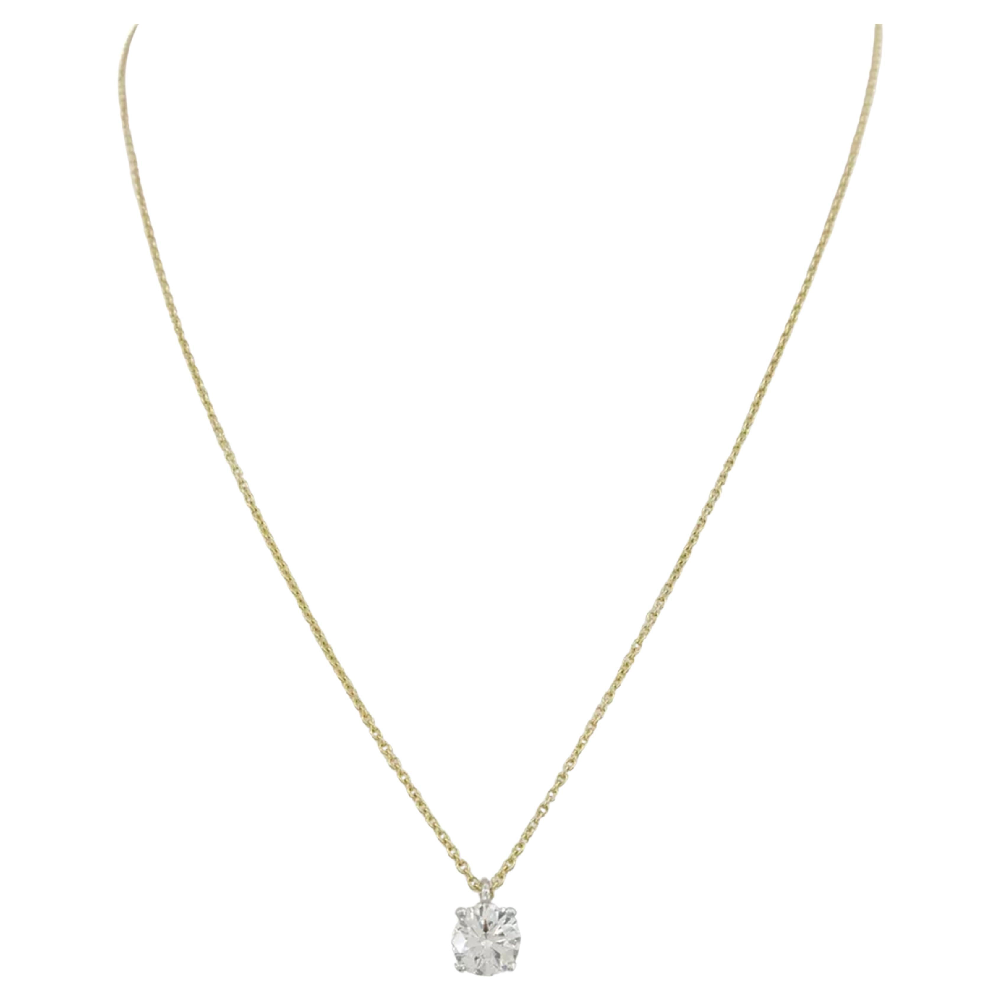 Tiffany & Co. pendant features a 0.77 ct round brilliant cut diamond set in platinum with an 18k yellow gold chain. The pendant and chain weigh 2.2 grams. The diamond has a weight of 0.77 ct, an H color grade, and VS1 clarity. It boasts an excellent