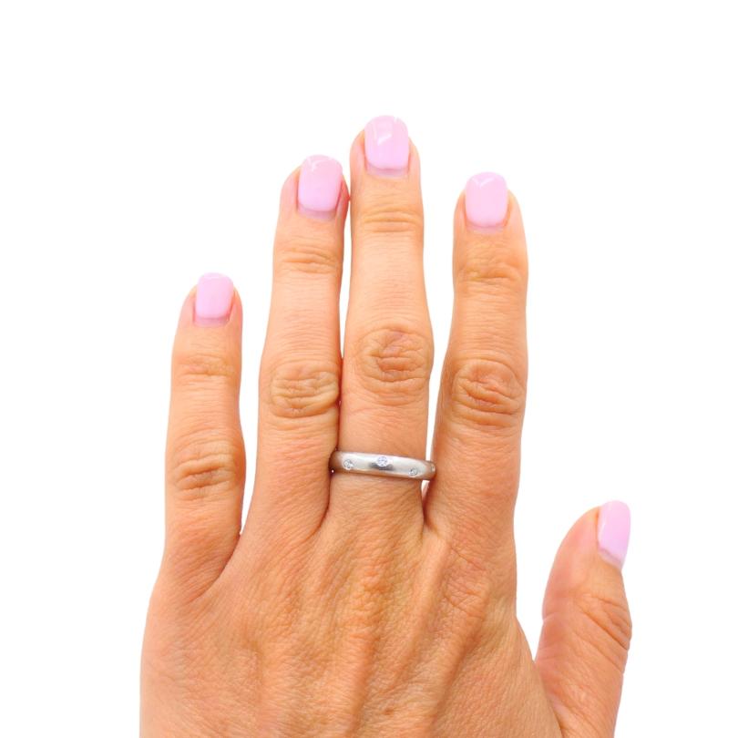 Este anillo Etoile de platino de Tiffany & Co. tiene nueve diamantes engastados en la banda.
El anillo tiene un acabado liso y pulido con bordes redondeados. Los diamantes están enrasados. El aspecto general del anillo es discreto, y los diamantes