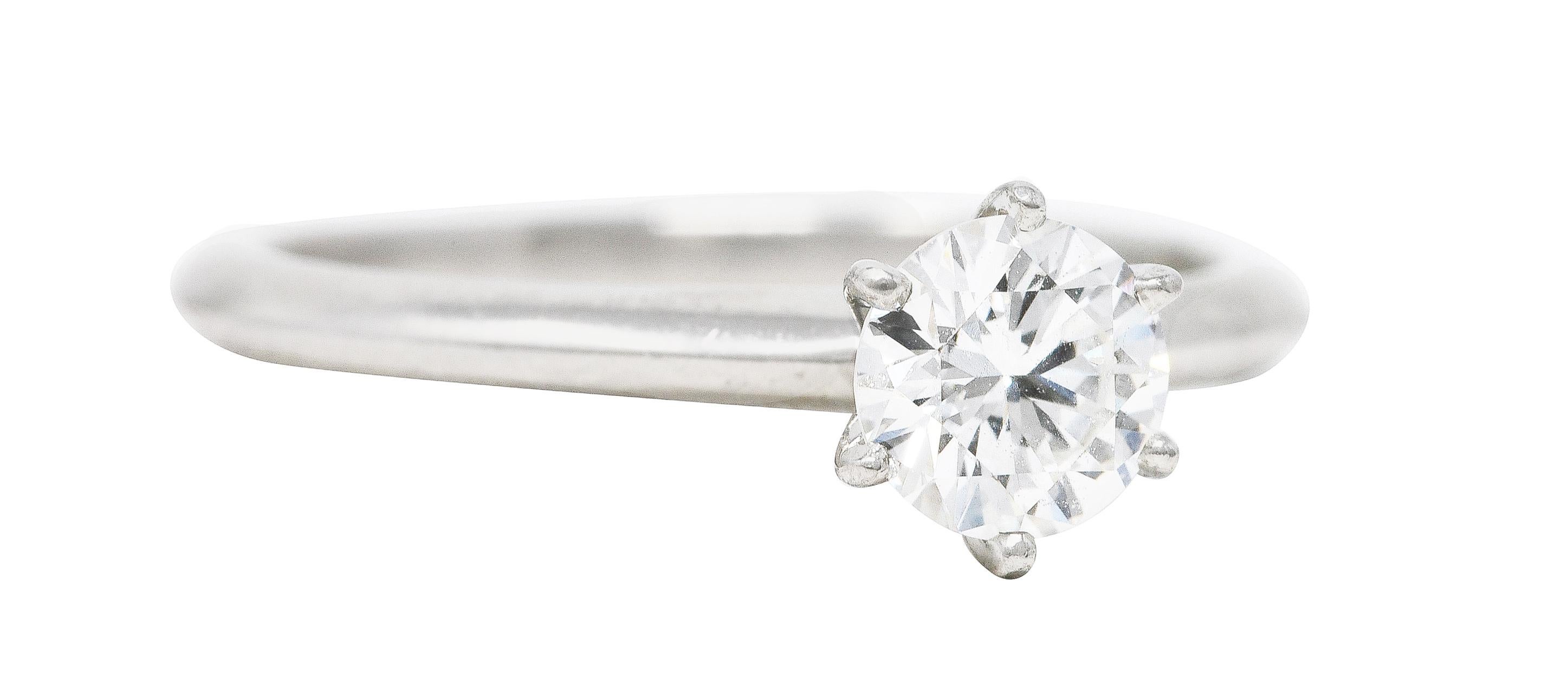 Centering a round brilliant cut diamond weighing 0.77 carat total - G color with SI1 clarity. Set in a classic Tiffany style setting with six prongs. Accented by knife's edge shank with high polish. Stamped for platinum. Numbered and fully signed
