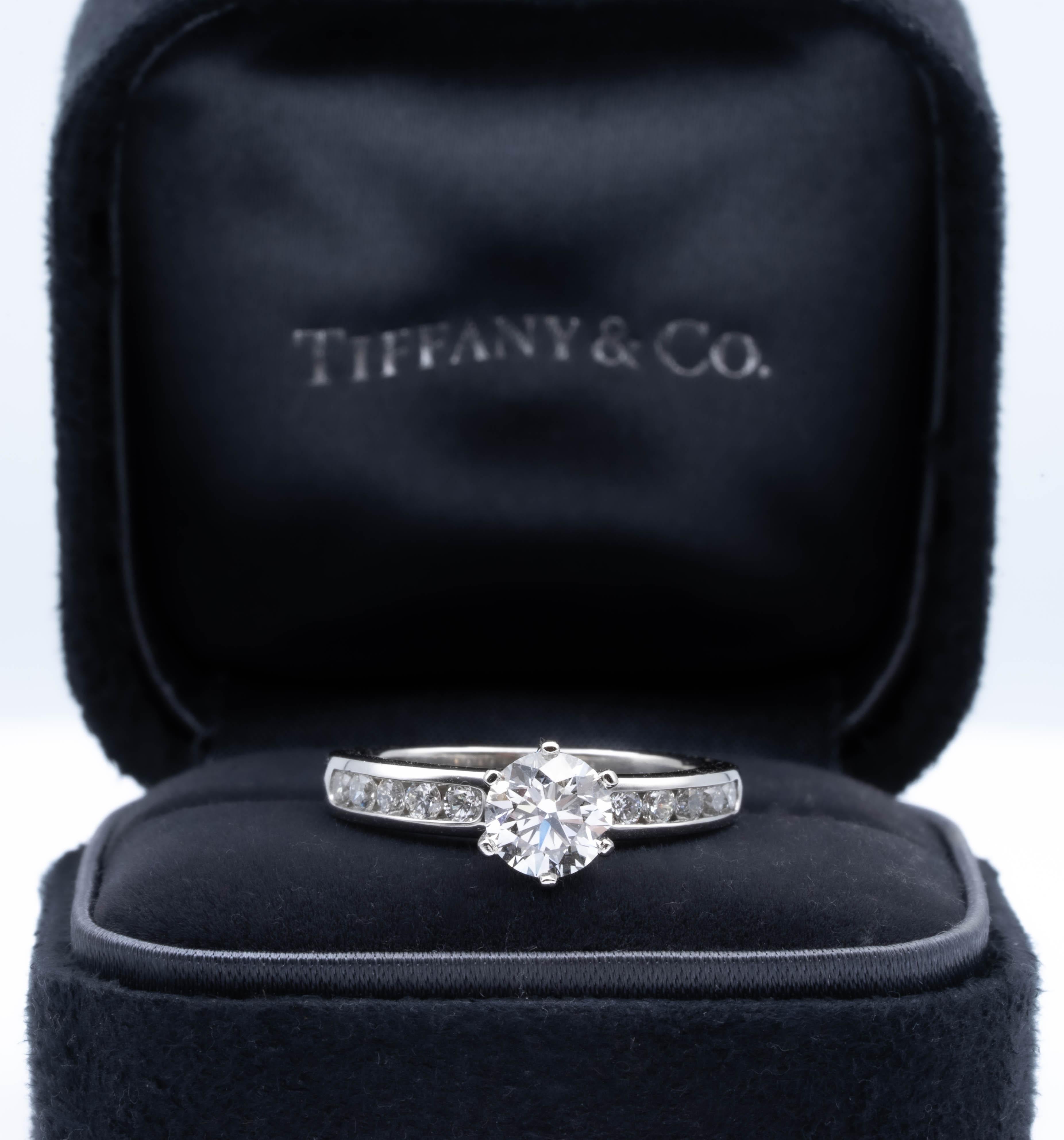 Tiffany & Co. Anillo de compromiso de diamantes con banda de diamantes engastados en canal firmada por Tiffany & Co. con un centro de 0,92 ct finamente elaborado en platino. El diamante central está flanqueado por 5 diamantes de talla brillante