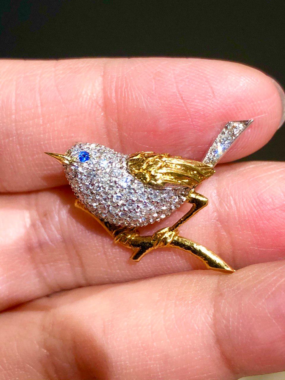 This elegant Tiffany & Co. brooch is crafted out of 18k yellow gold in the shape of a charming bird and accented with sparkling round diamonds of an estimated 0.65 carats and a blue sapphire eye. Made in United States circa 1960s. In original pouch.