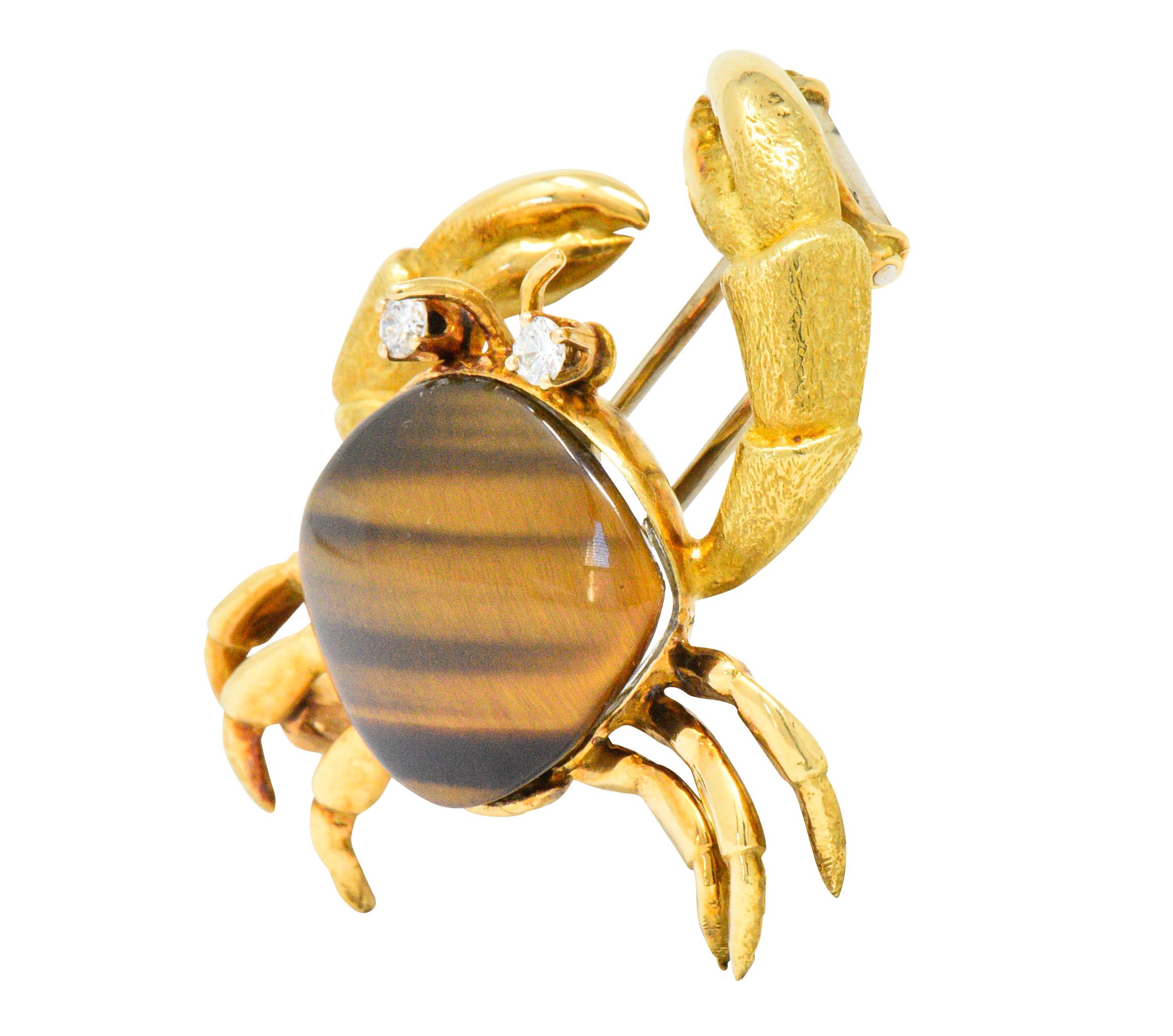 Featuring a dimensional crab design with an 18kt gold foundation depicting textured claws and 6 back legs

Two prong set round brilliant diamond eyes weighing 0.14 carat, eye clean and bright

Body centers a rounded triangular and bezel set cabochon