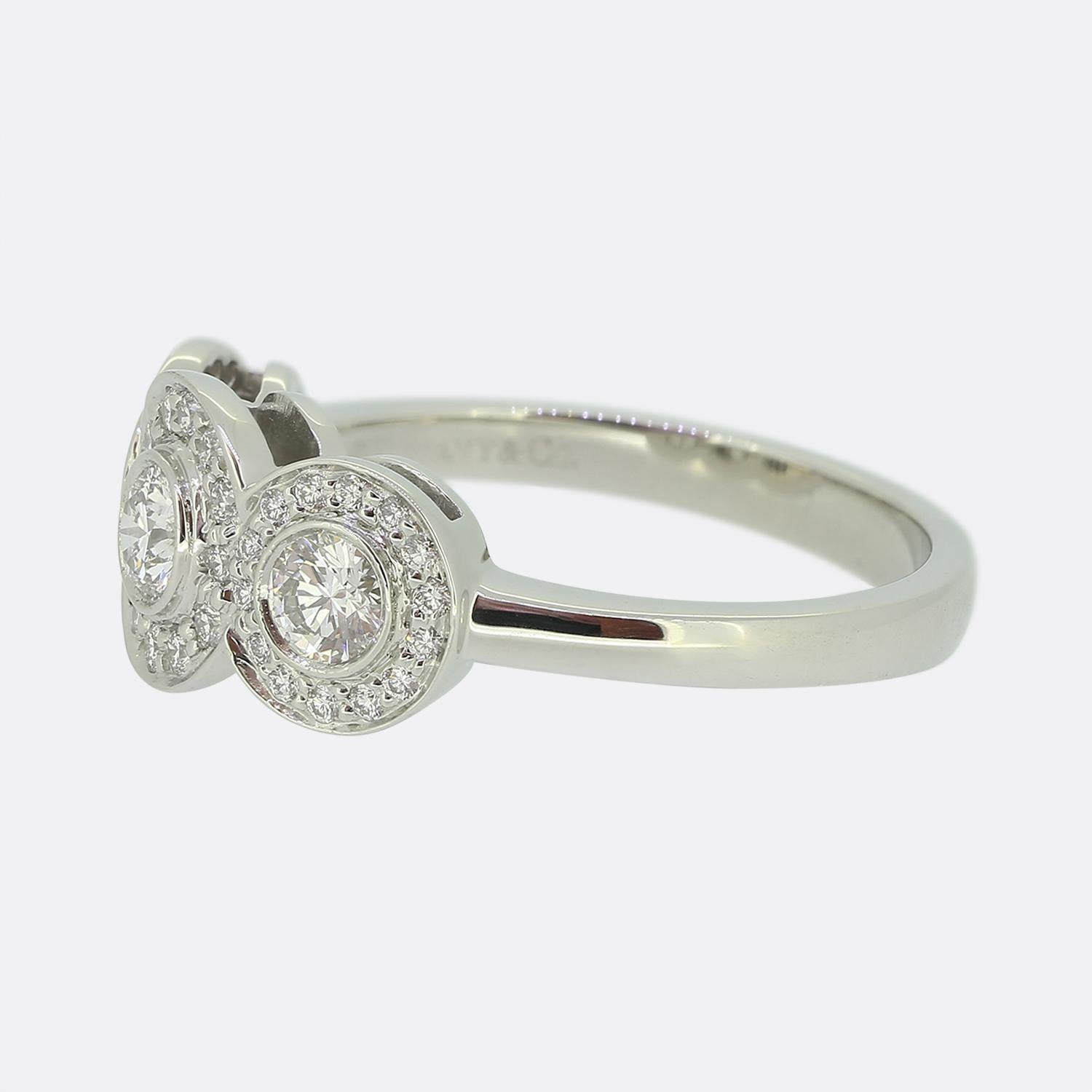 This is a platinum Tiffany & Co. diamond circlet ring. The face of the ring showcases a trio of clusters; each larger rub-over set round brilliant cut diamond is circulated by a halo of smaller claw set matching stones. 

Condition: Used (Very