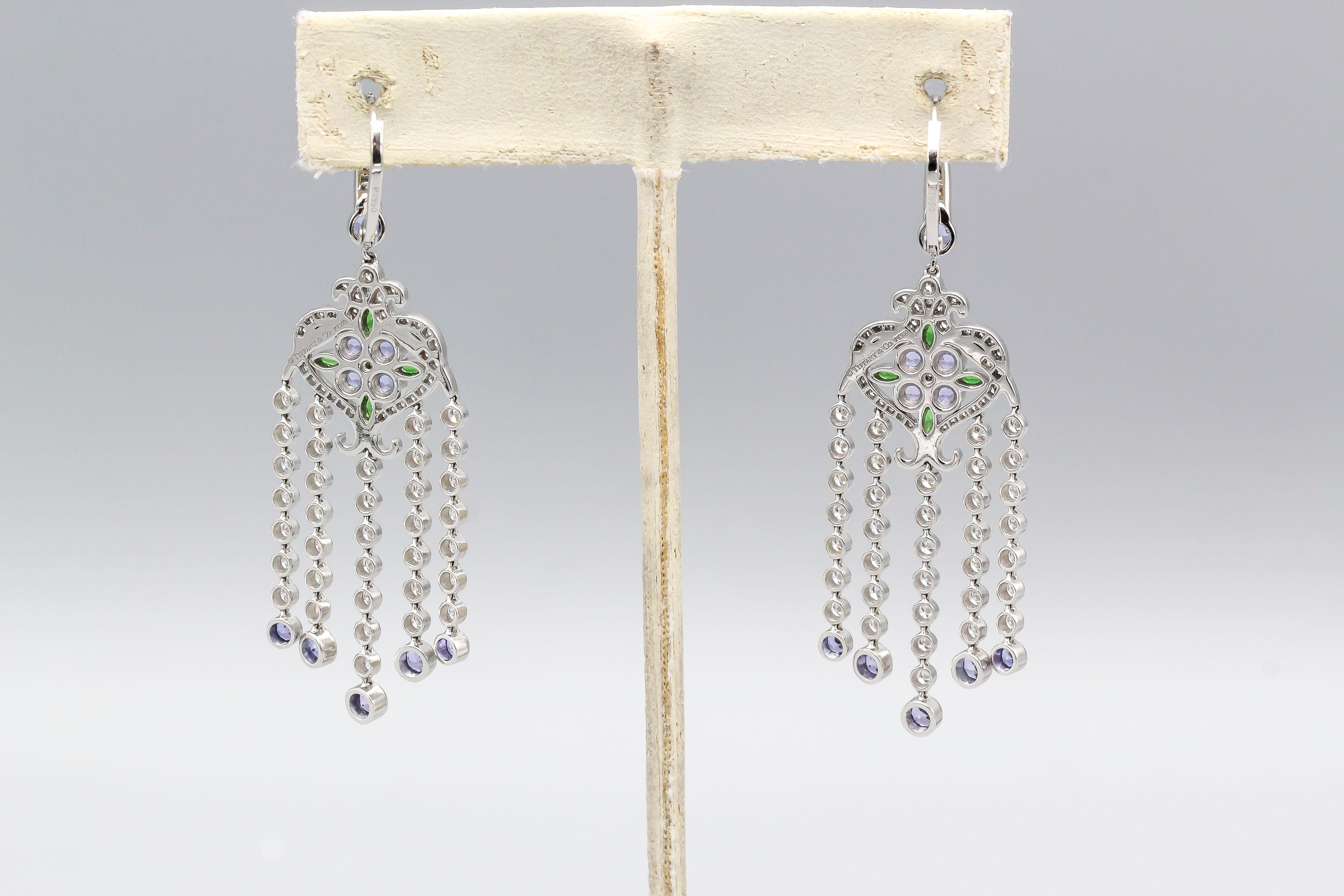 Elegant diamond, tanzanite, tsavorite and platinum dangle earrings by Tiffany & Co. They feature rich color stones, as well as high grade round brilliant cut diamonds over a platinum setting.

Hallmarks: Tiffany  & Co., PT950, copyright.