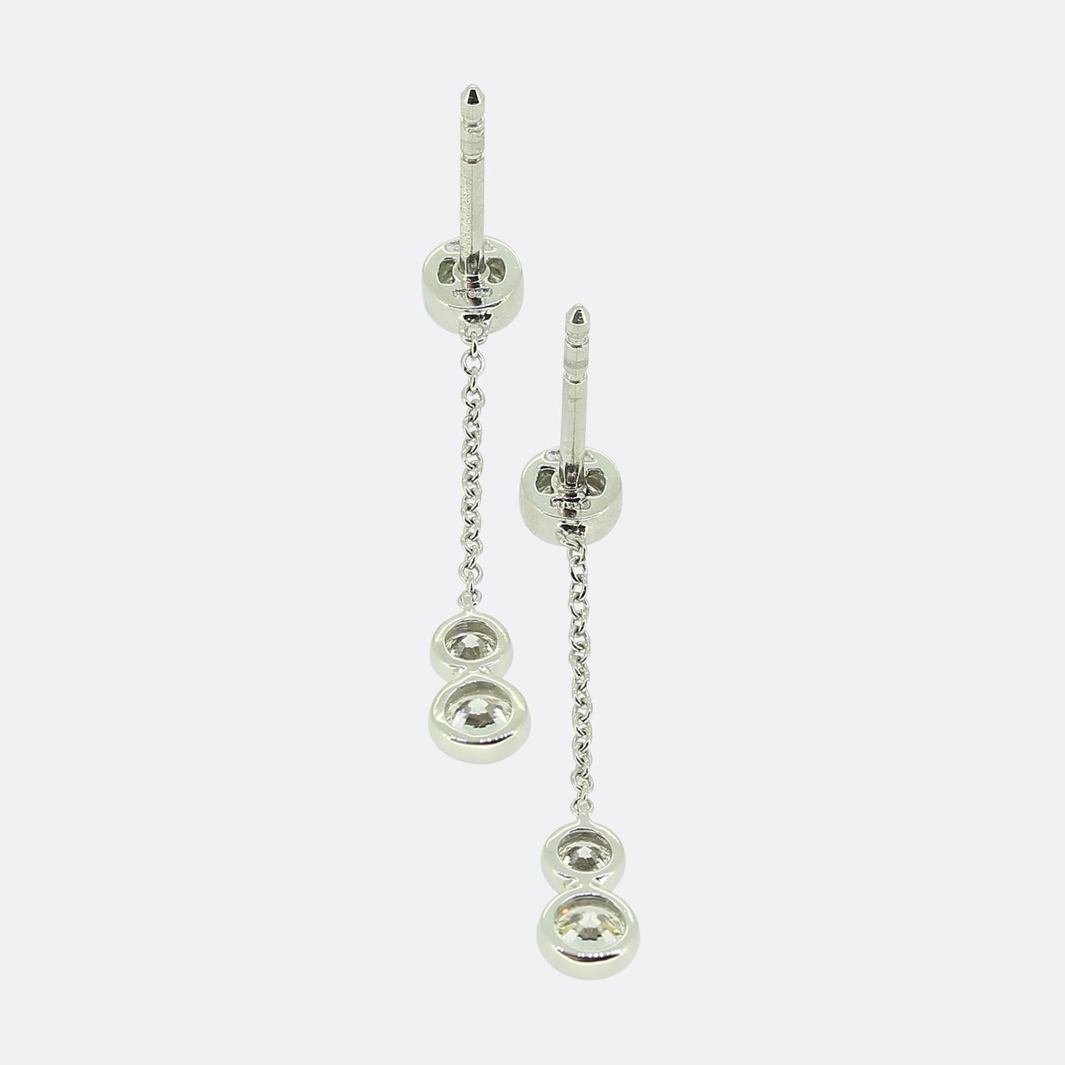 Hier haben wir ein entzückendes Paar Diamant-Ohrringe des weltbekannten Schmuckdesigners Tiffany & Co. Jeder Ohrring besteht aus einem einzelnen runden Brillanten und einer Platinkette, die zu zwei weiteren runden Brillanten führt.

Zustand:
