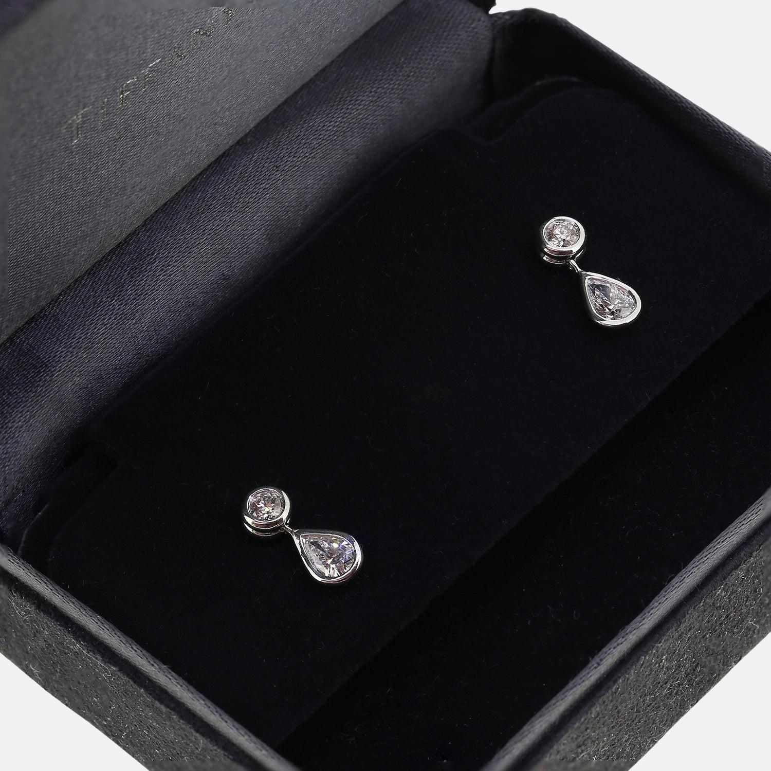 Ecco un delizioso paio di orecchini di diamanti a goccia della famosa gioielleria Tiffany & Co. Ogni pezzo è stato realizzato in platino e mostra un singolo diamante rotondo taglio brillante con un diamante a forma di pera che pende liberamente al