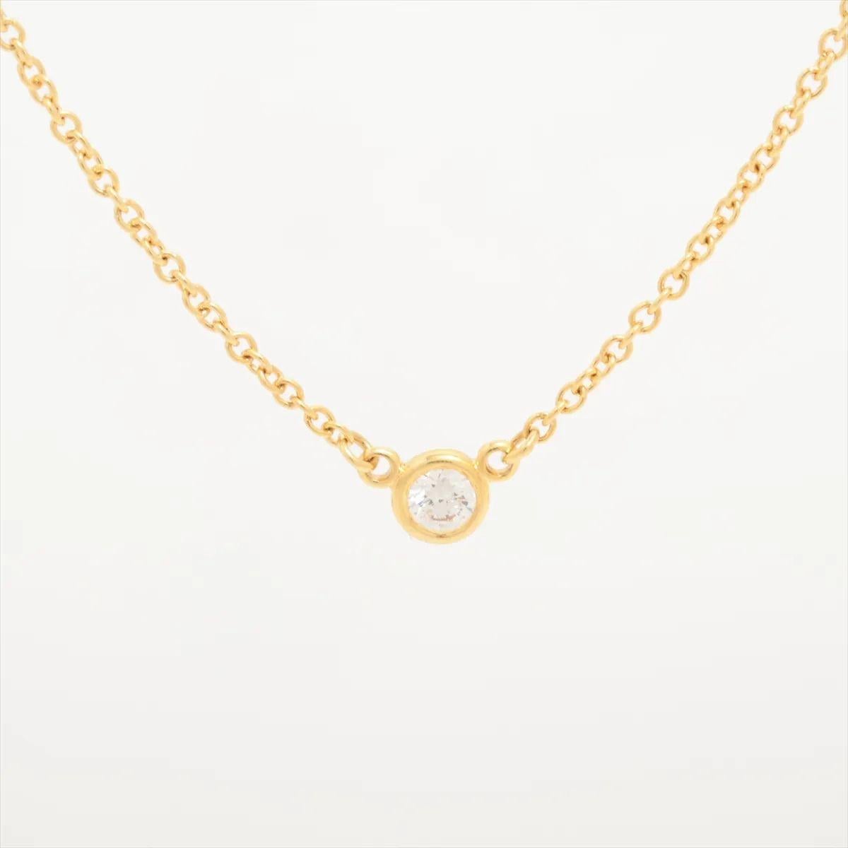 The Tiffany & Co. Diamond by the Yard Necklace in yellow gold features a single bezel-set round brilliant diamond as its elegant centerpiece. Crafted in luminous 18k yellow gold, the delicate chain draws attention to the centrally placed diamond,