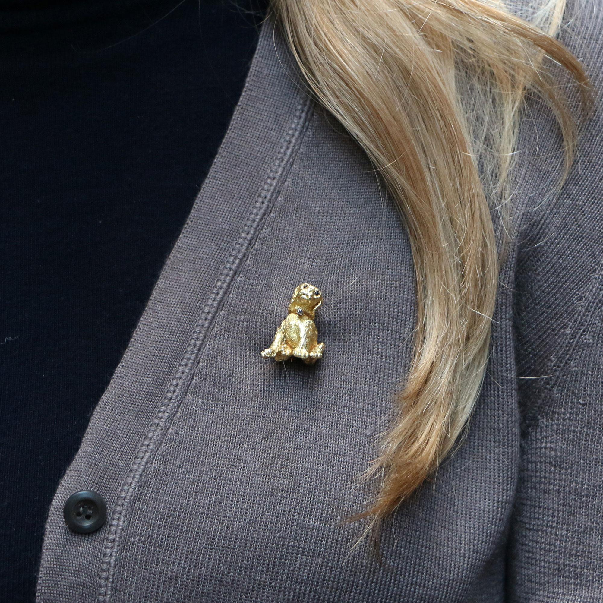 A beautifully detailed signed Tiffany & Co. puppy brooch set in 18k yellow gold. 

The brooch depicts a sitting puppy and is set with two round brilliant cut sapphire eyes and one round brilliant diamond in the collar. The piece is then secured to