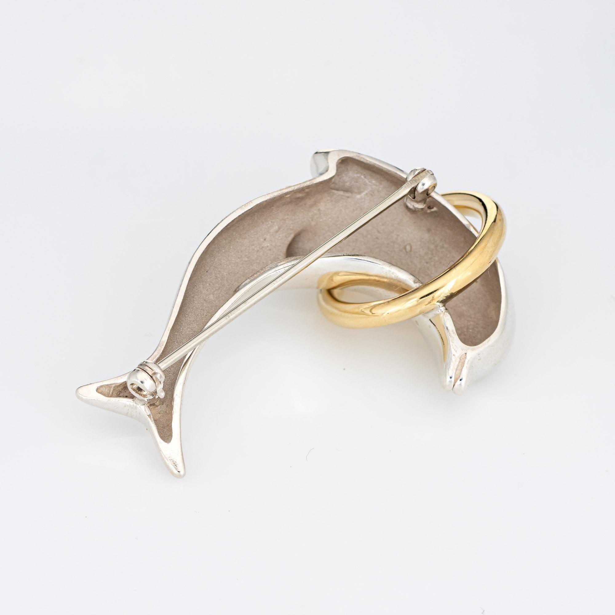 Finely detailed vintage Tiffany & Co dolphin brooch crafted in sterling silver & 18k yellow gold (circa 1990s). 

The sweet brooch depicts a dolphin in full flight, jumping through an 18k yellow gold hoop. 

The brooch is in very good condition and