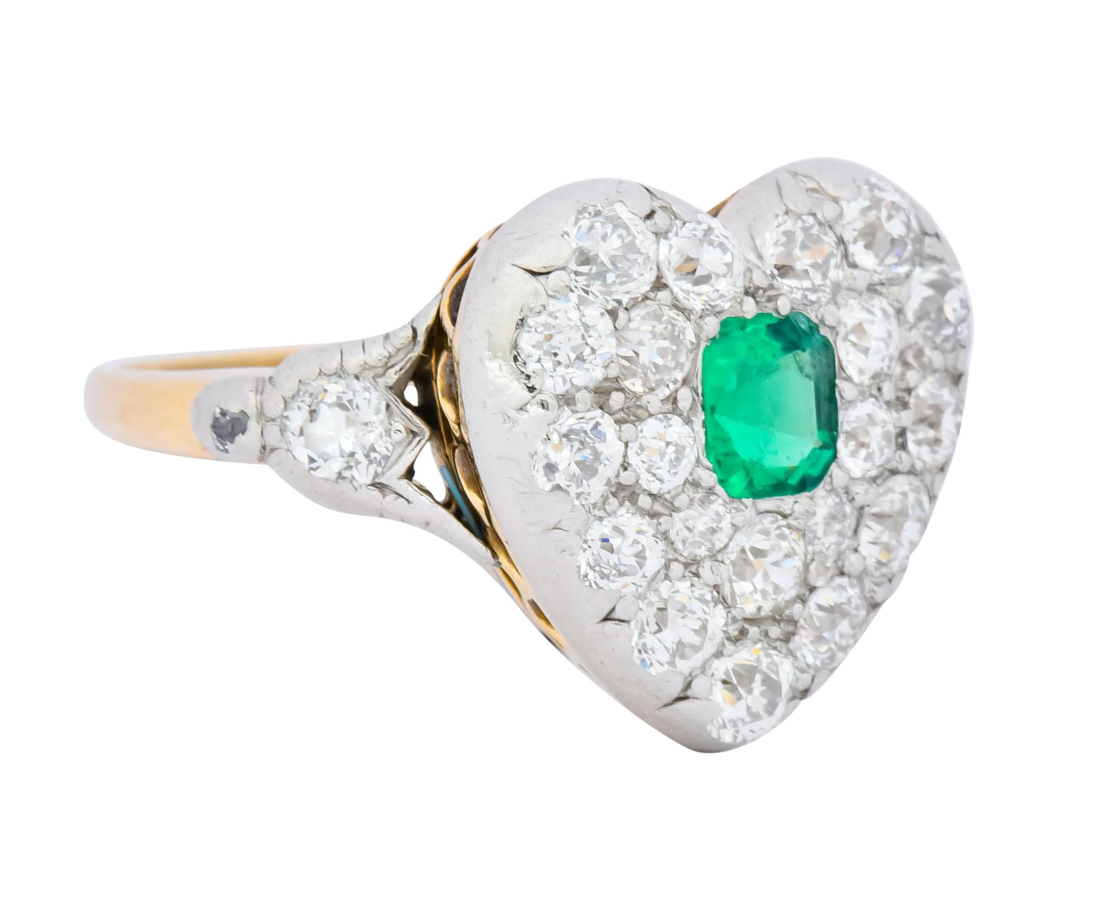 Cluster style ring shaped as a heart centering a rectangular step cut emerald weighing approximately 0.25 carat, transparent and a bright saturated green

Surrounded by old European cut diamonds weighing approximately 1.17 carats, G/H color and VS