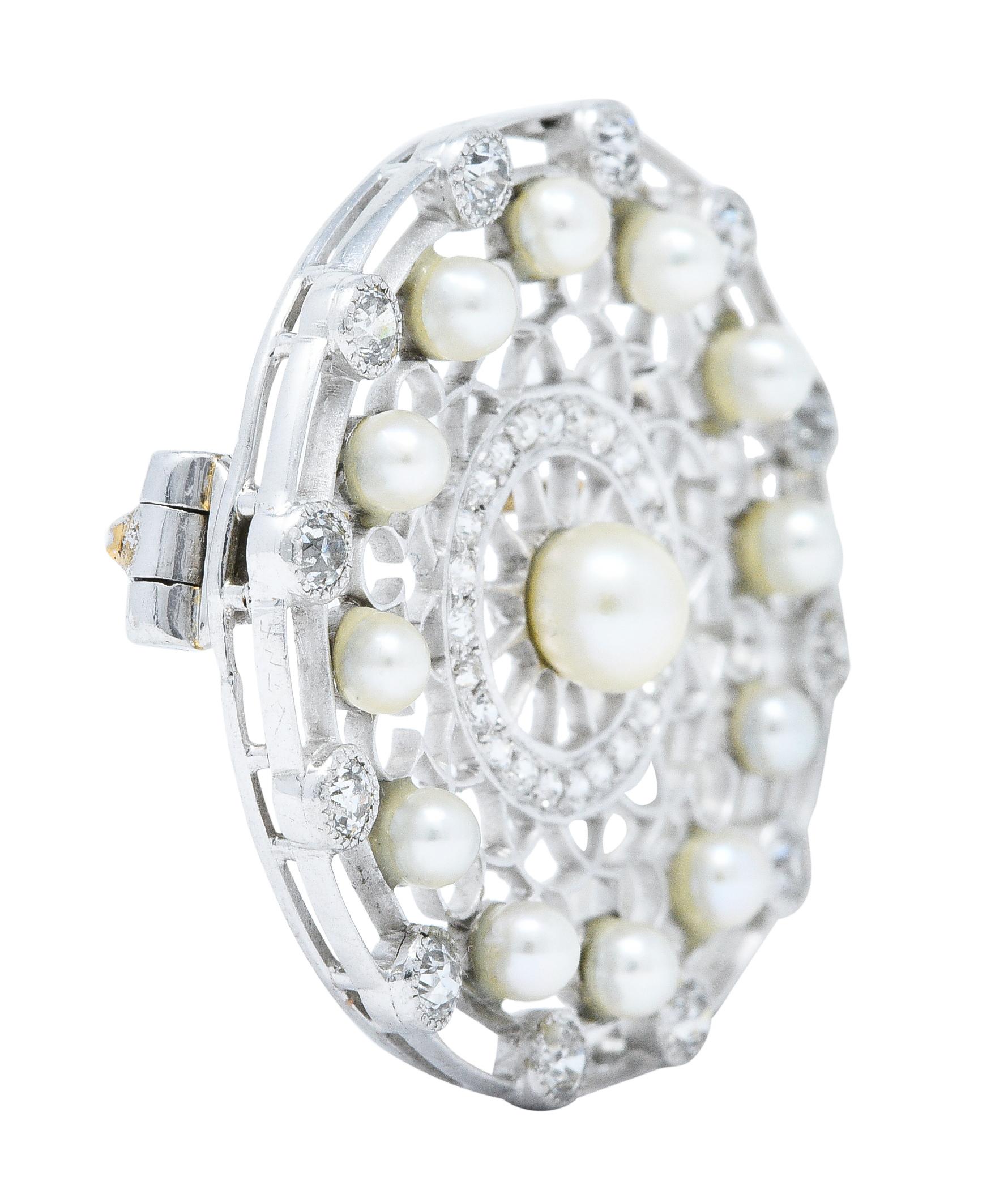 Circular brooch features a pierced trellis design and centers a 4.5 mm button pearl

Surrounded by a halo of 2.5 mm pearls - all are white to cream in color with very good luster

Accented by two concentric halos of old European cut