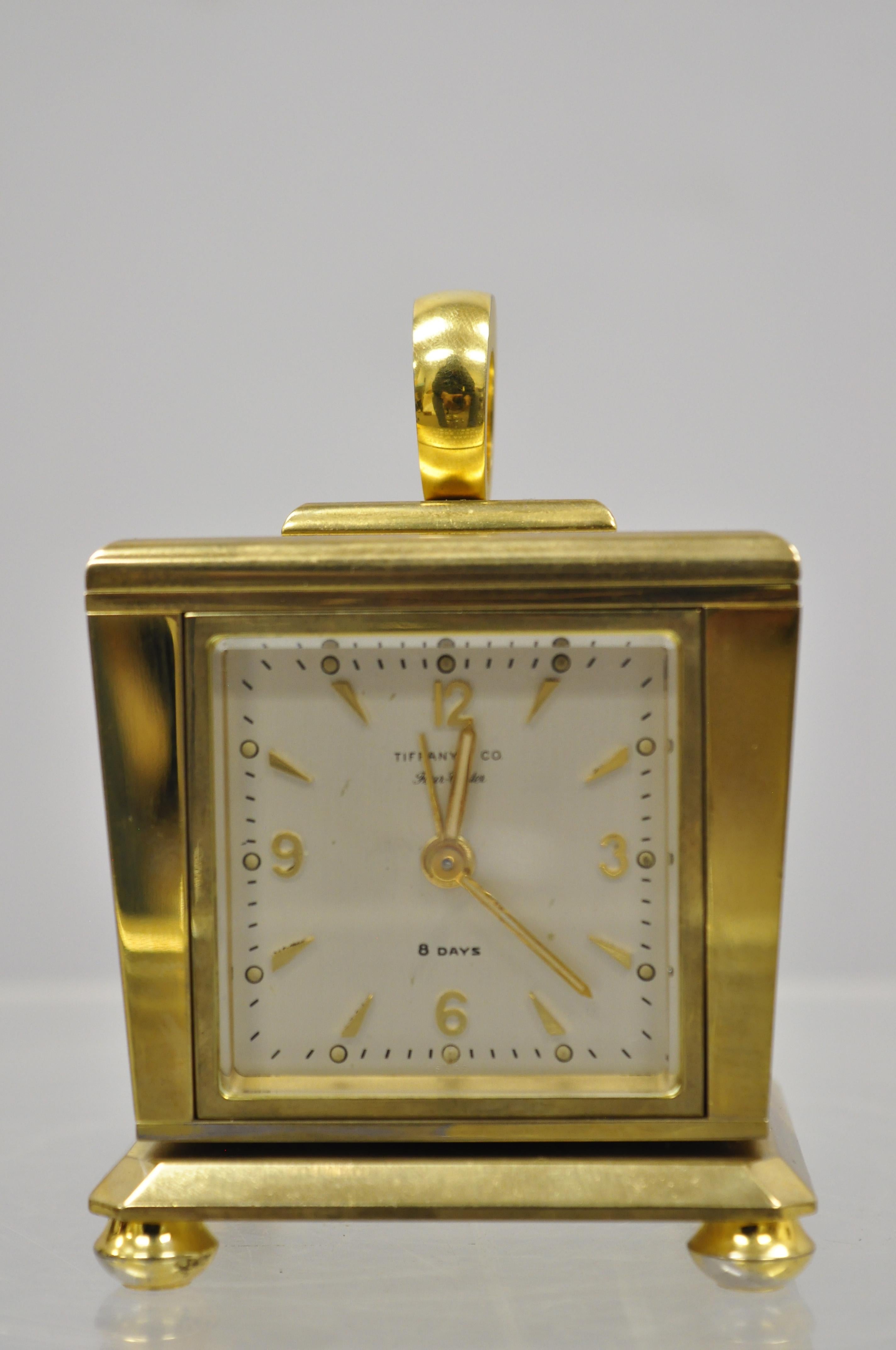 Tiffany & Co. eight day brass four caster revolving small desk clock. Item includes a solid brass revolving case, Swiss made, alarm clock, barometer/thermometer, hygrometer. Engraved to top of case, circa mid-20th century. Measurements: 4.5
