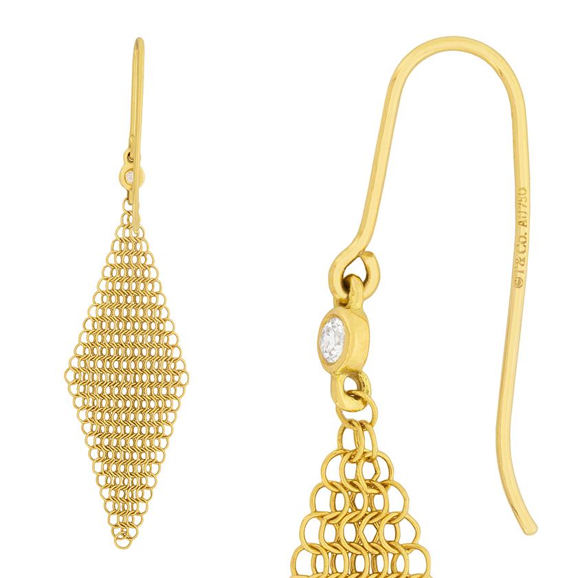 Glamorous yet understated, these Tiffany & Co. earrings are stunning. A diamond shaped web of 18 carat yellow gold mesh drapes down from a rub-over set diamond. Each diamond is 0.03 carat and is an excellent F colour and VS clarity.  
Gemstone: