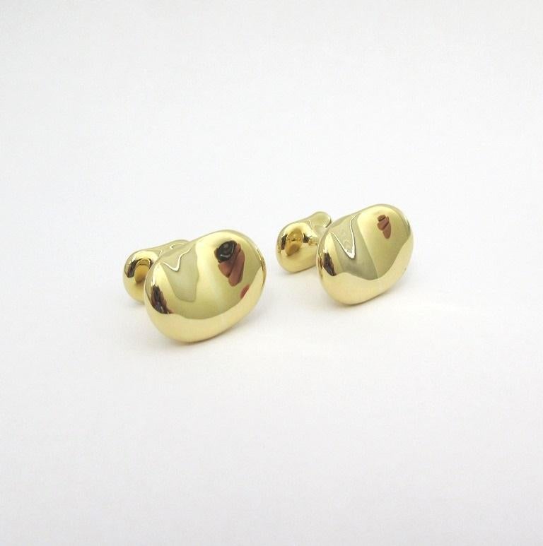 TIFFANY & Co. Elsa Peretti 18K Gold 18mm Breite Bohne Manschettenknöpfe Manschettenknöpfe

Metall: 18K Gold 
Gewicht: 19.0 Gramm
Breite: 18 mm breit
Punze: TIFFANY&Co. 18K PERETTI 
Tiffany-Preis: $6.800
Zustand: Ausgezeichneter Zustand, mit