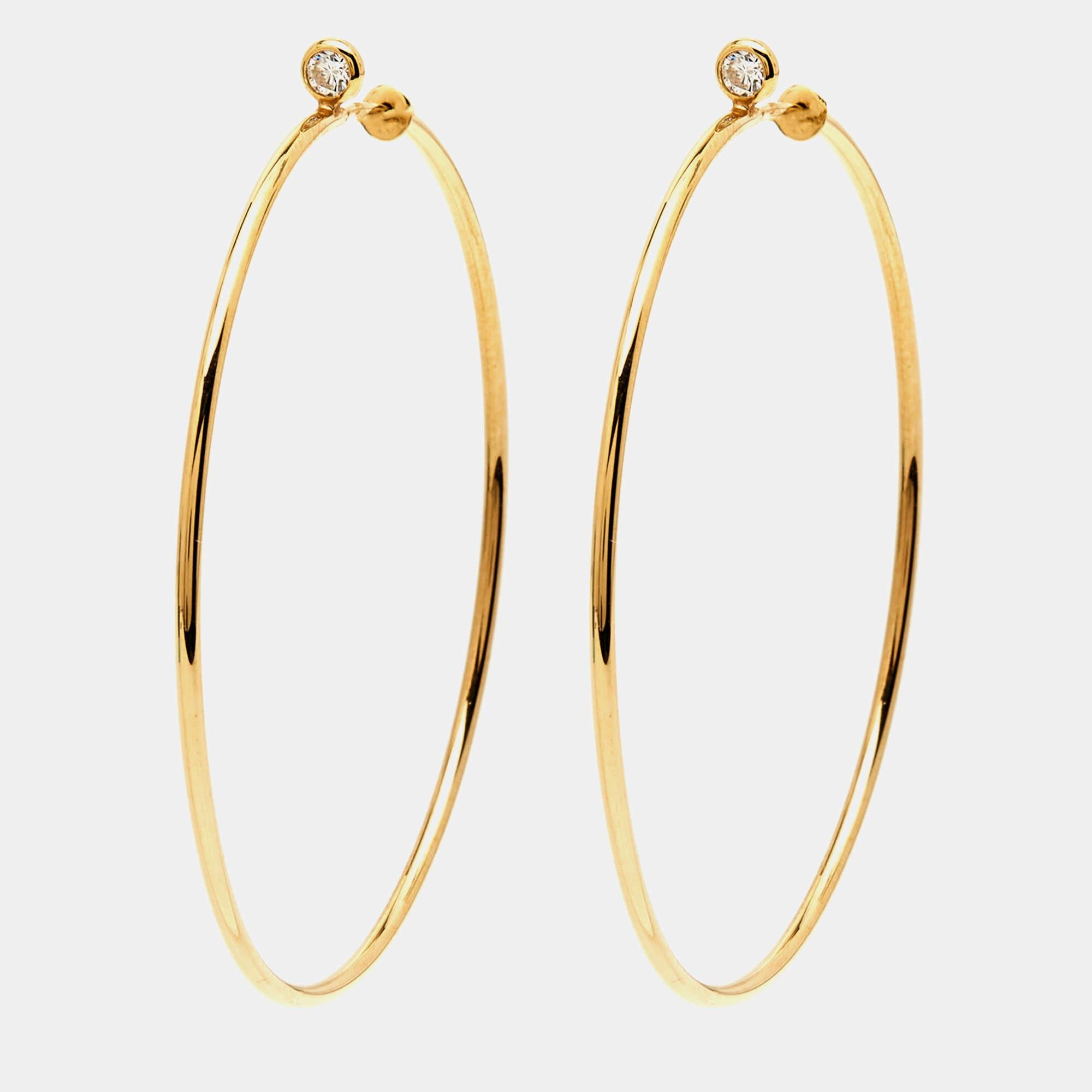 Discover elegance with Tiffany & Co.'s Elsa Peretti hoop earrings. Crafted from 18k yellow gold, these hoops exude timeless beauty. Each earring features delicate diamonds, adding a touch of sparkle to any ensemble. Elevate your style with these