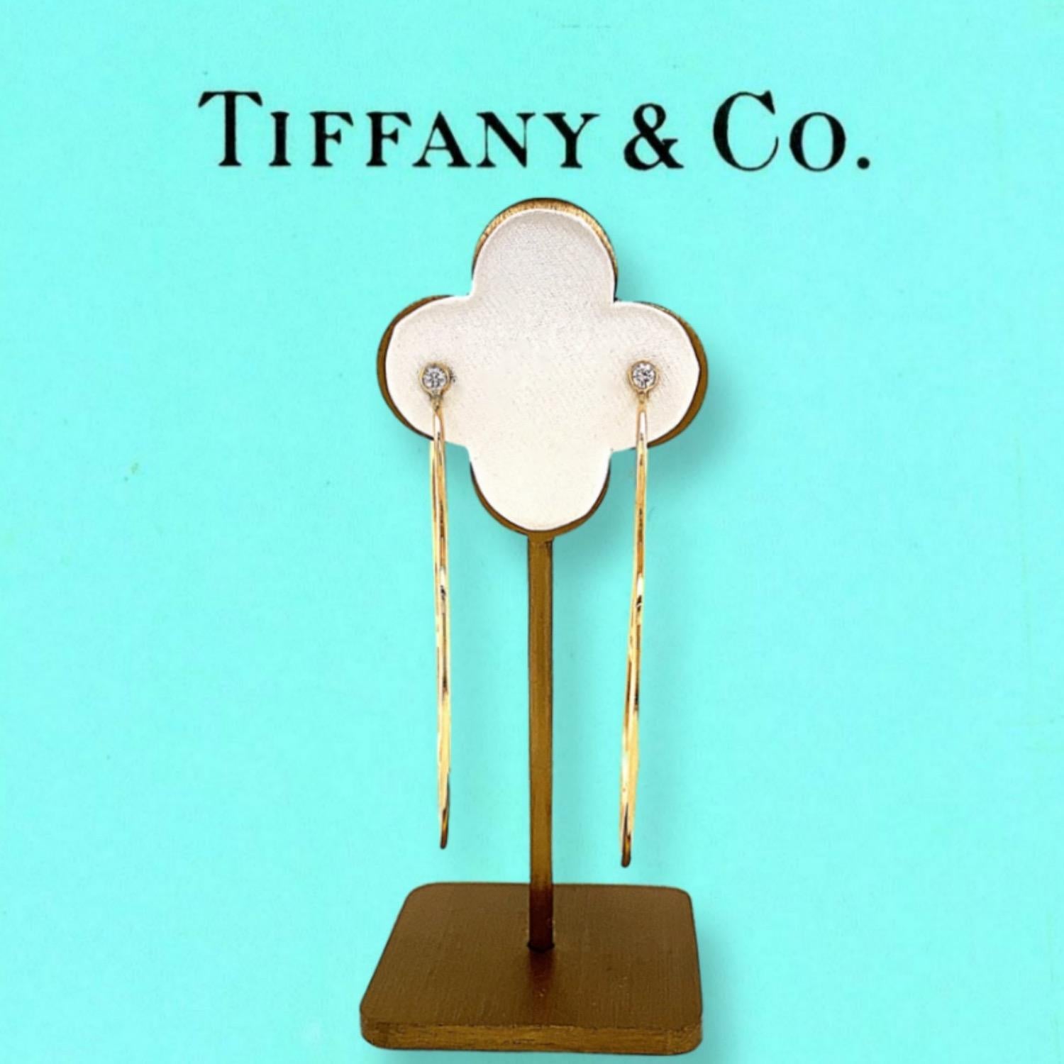 Tiffany & Co. Elsa Peretti Diamond Hoop Earrings
Style:  27911544
Metal:  18kt Yellow Gold
Size:  Large
TCW:  0.12 tcw
Main Diamond:  2 Round Brilliant DiamondsBezel Set
Color & Clarity:  F - VVS
Hallmark:  T&CO.  Elsa Peretti AU750
Includes:  T&C