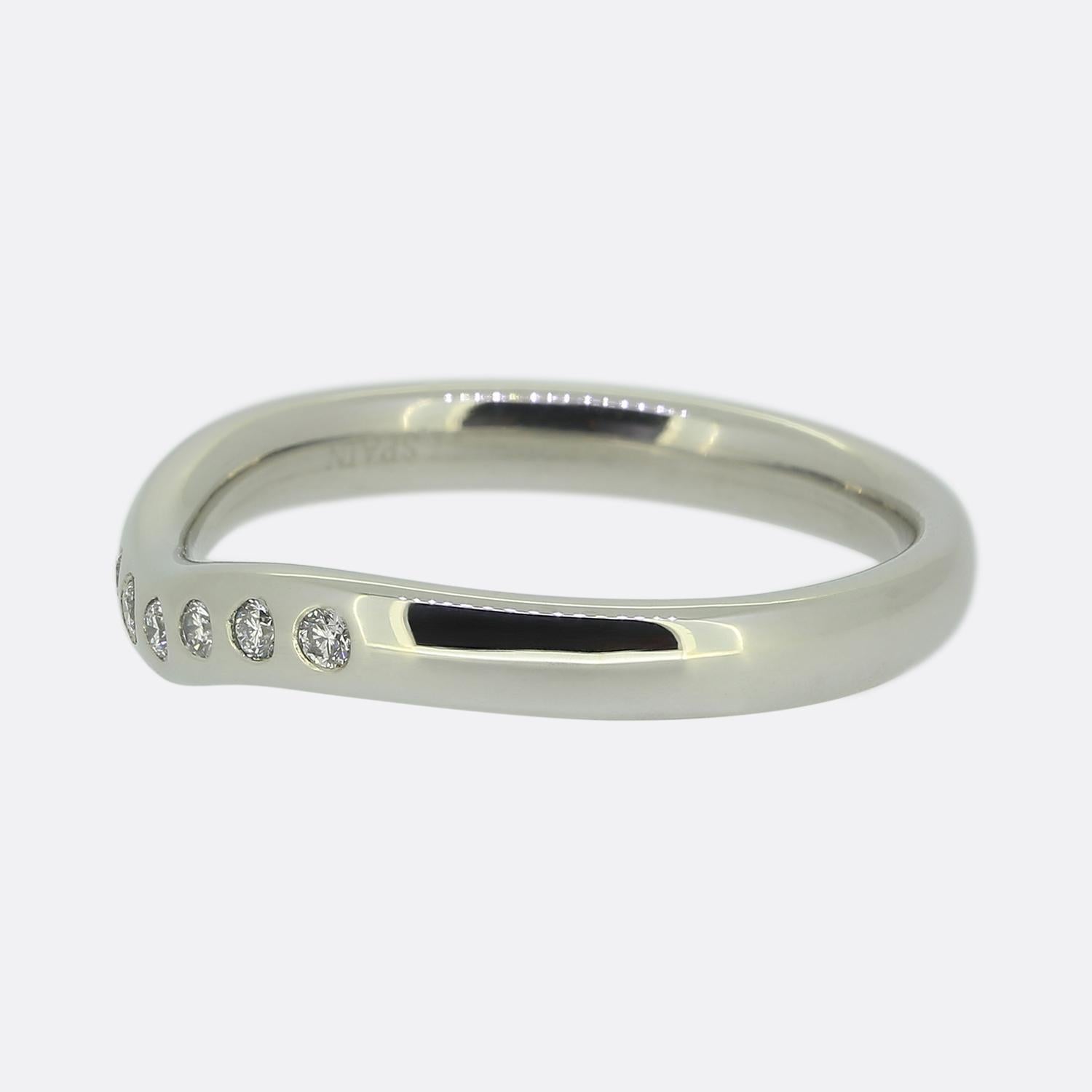 Here we have a diamond wedding band ring from the world renowned jewellery designer, Tiffany & Co. The band has been crafted from platinum and features seven round brilliant cut diamonds in a rub-over setting atop a curved face. This ring forms part