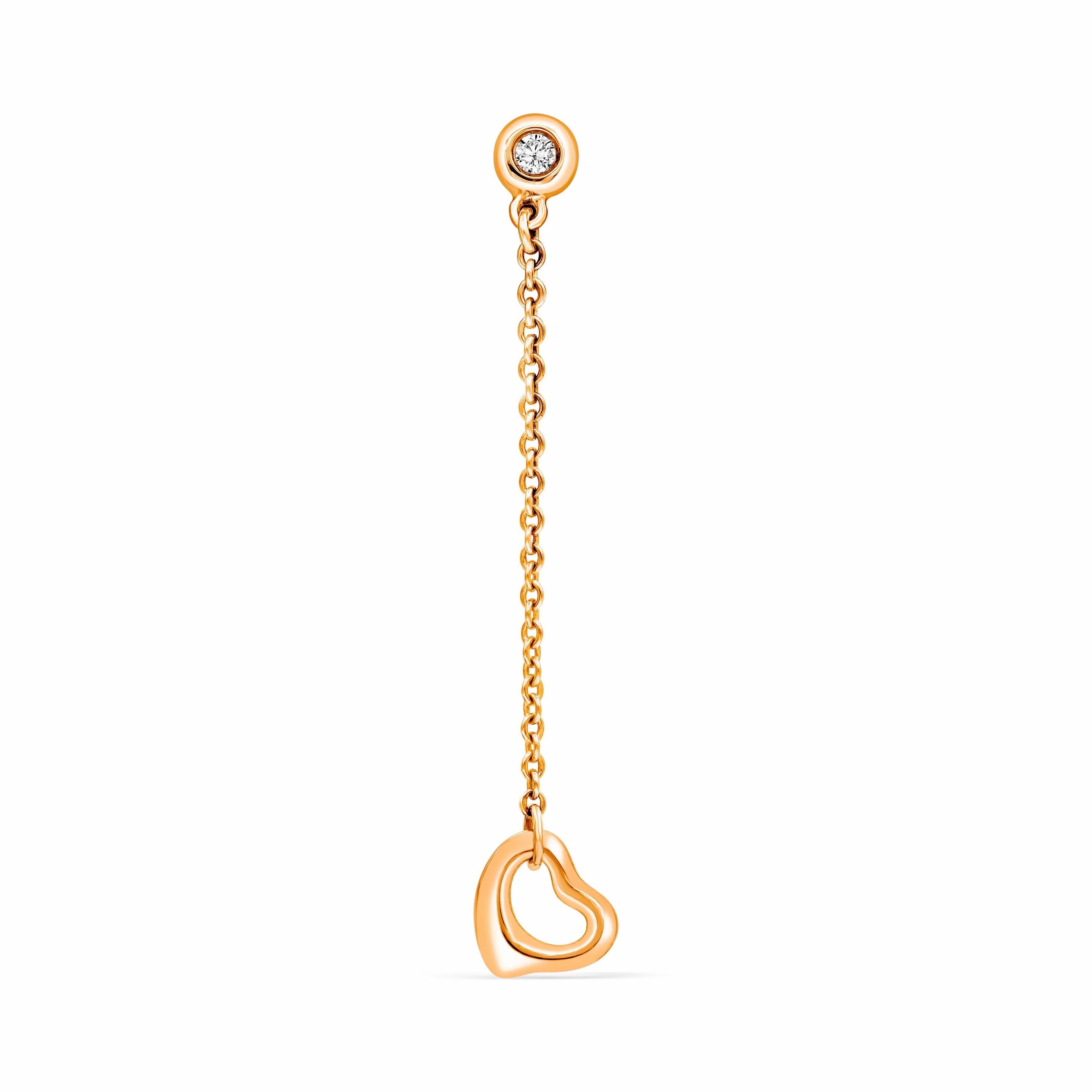 Drop earrings made in 18 karat rose gold suspending two, rose gold open hearts approximately 7 millimeters. A bezel set round diamond elegantly holds the open heart drop. Designed by Elsa Peretti for Tiffany & Co.