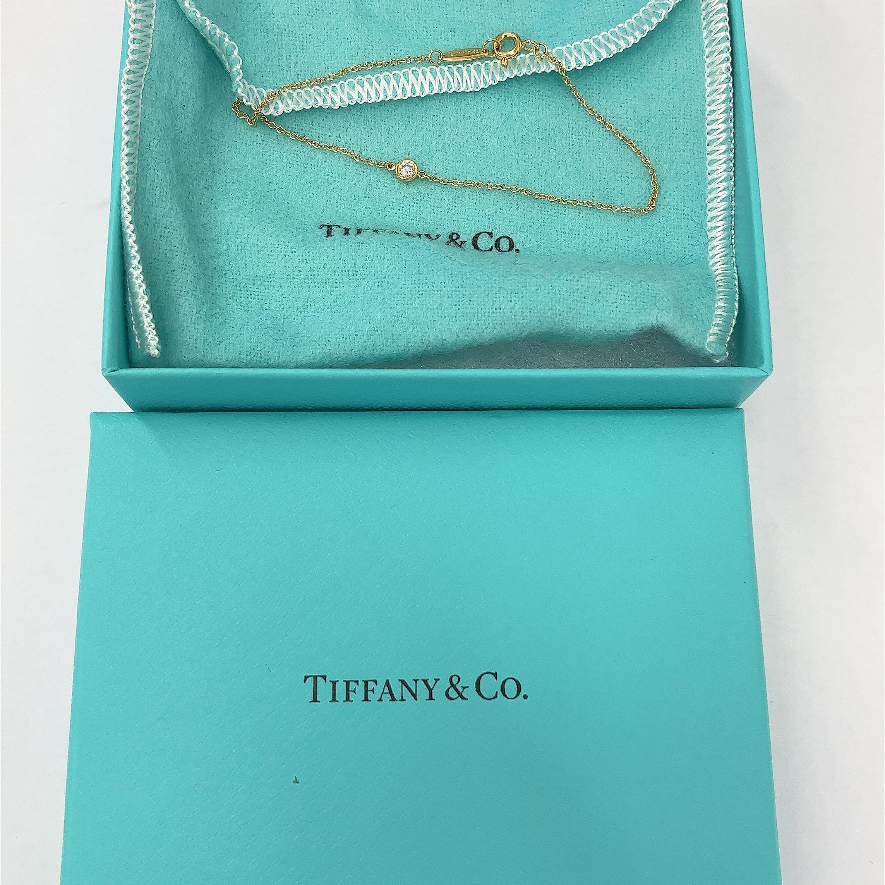 Erhöhen Sie Ihre Eleganz mit der Tiffany & Co. Elsa Peretti Diamonds by the Yard Einzelne Diamant-Halskette in 18ct Gelbgold. Dieses exquisite Schmuckstück mit einem einzelnen strahlenden Diamanten, der an einer zarten Kette hängt, wurde von Elsa