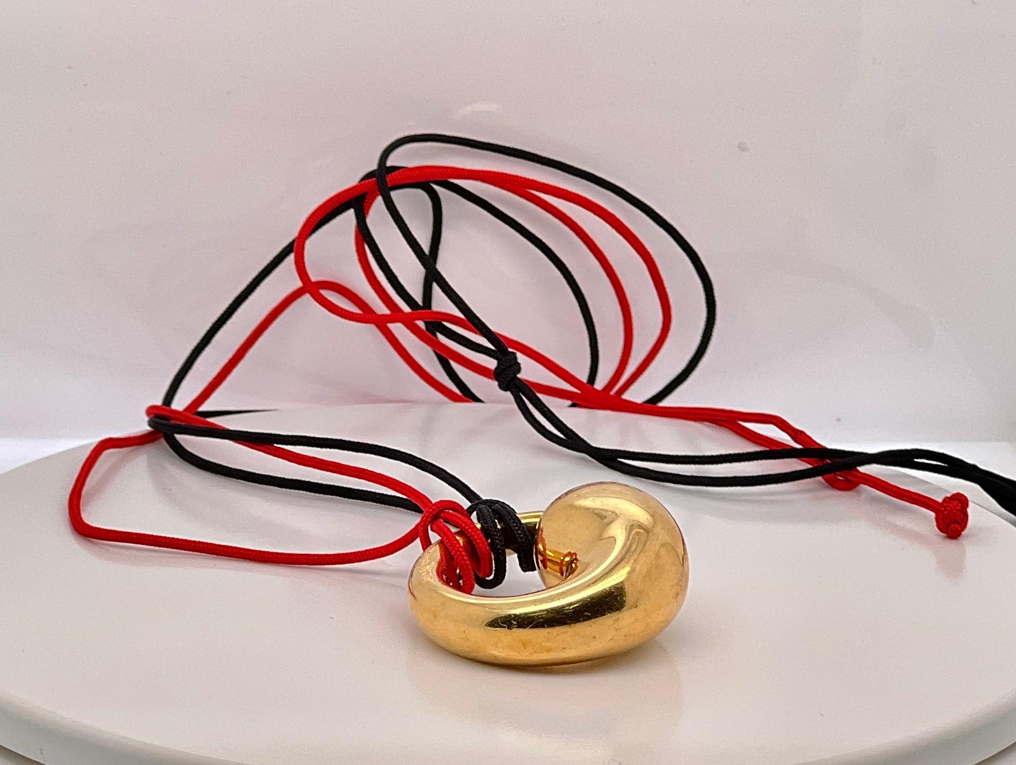 Tiffany & Co. Elsa Peretti Eternal Circle 18k Gold Pendant Necklace 

Exquisite large size eternal circle in 18k gold on black and red cord, can be worn on either cord. 
All hallmarked and signed. 
Pendant measures approx. 1 1/4