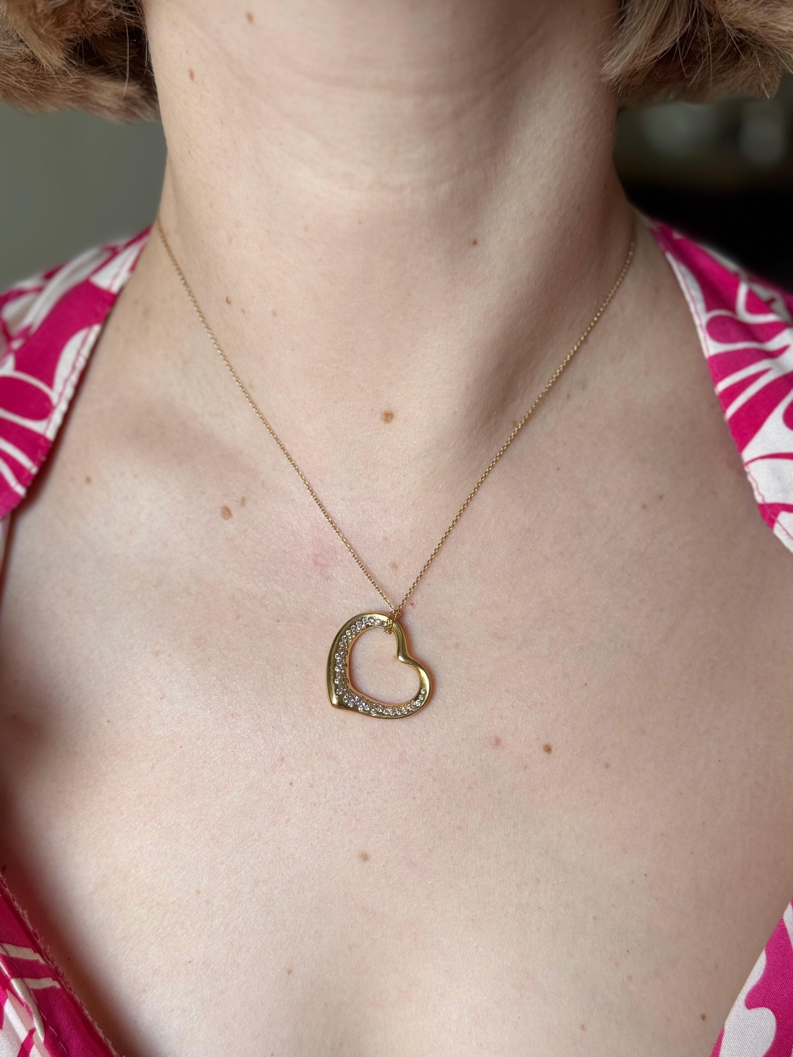 Collier en or jaune 18 carats avec pendentif en forme de cœur ouvert, conçu par Elsa Peretti pour Tiffany & Co.
Le pendentif est orné d'environ 0,54ctw de diamants G/VS. 
La chaîne du collier est longue de 17
