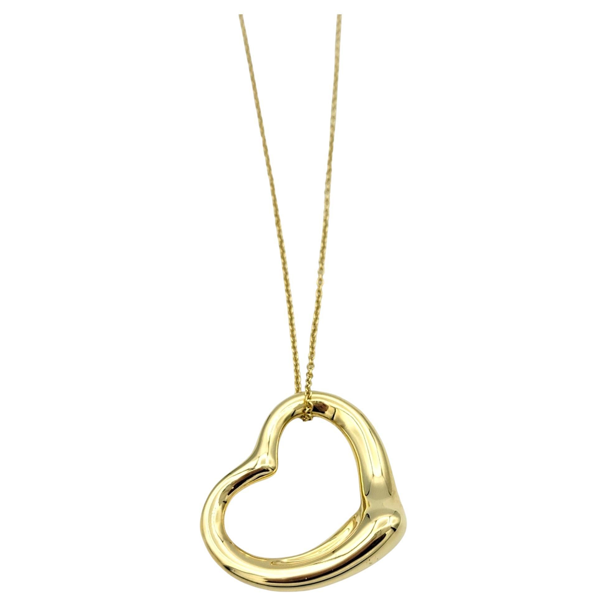 This Tiffany & Co. Elsa Peretti Open Heart Necklace, crafted in luxurious 18 karat yellow gold, is a timeless and iconic piece of jewelry. Designed by the renowned artist Elsa Peretti, this necklace features a delicate open heart pendant that exudes