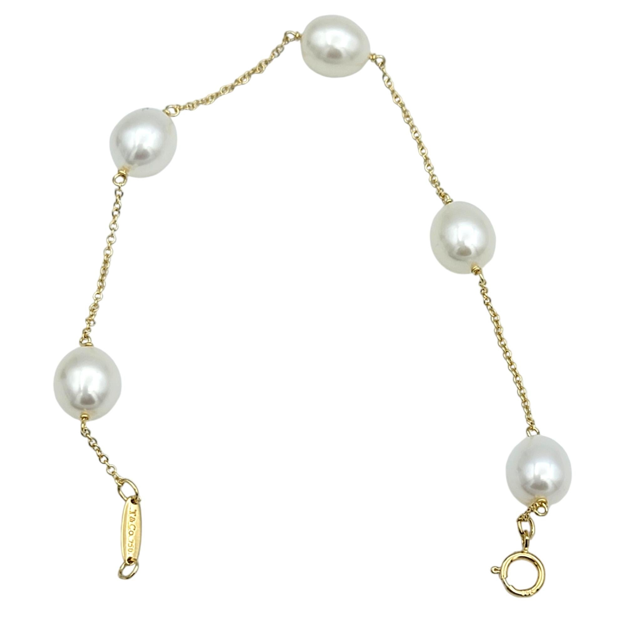 Discover the understated elegance of Tiffany & Co. with the iconic Elsa Peretti 'Pearls by the Yard' bracelet. This exquisite piece features a delicate 18 karat yellow gold chain adorned with 5 luminous pearls, each carefully spaced to create a