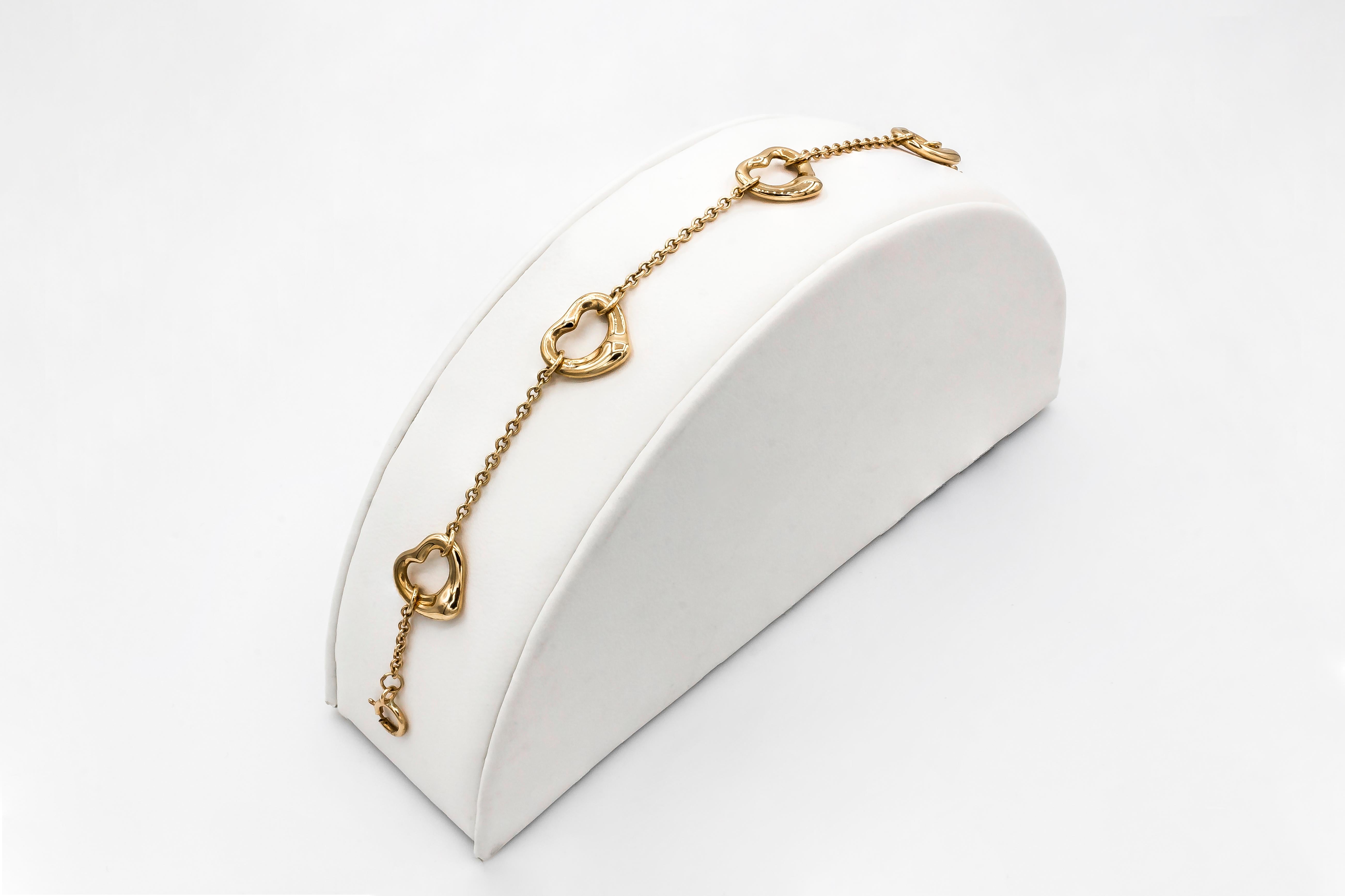 A simple bracelet showcasing 5 rose gold open hearts evenly-spaced in an 18 karat rose gold chain. The hearts are approximately 11 millimeters wide. Designed by Elsa Peretti for Tiffany & Co.