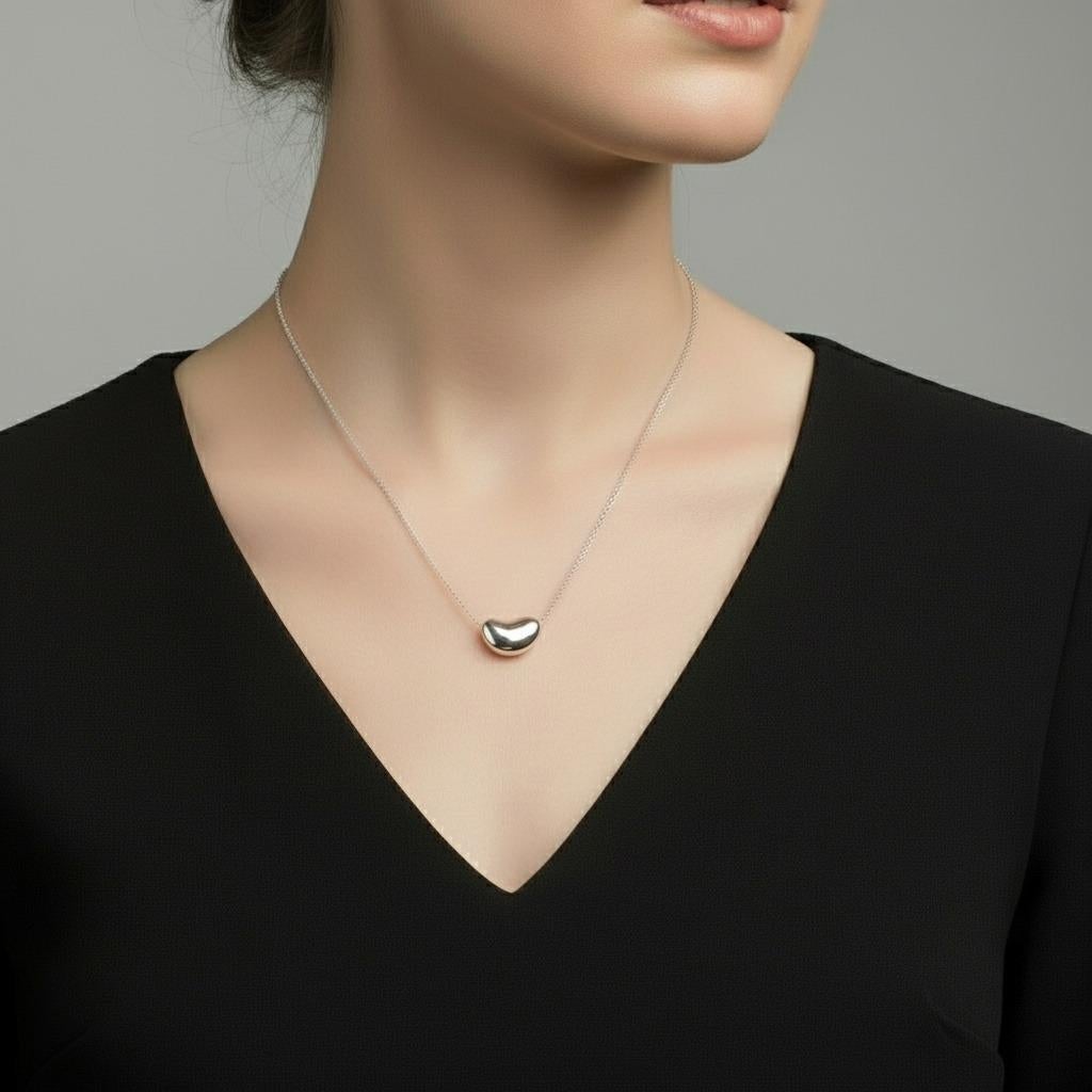 Eleg, c'est l'élégance intemporelle avec ce modèle emblématique de Tiffany & Co. Le collier de haricots d'Elsa Peretti, un chef-d'œuvre de la joaillerie contemporaine qui captive les collectionneurs depuis des décennies. Cette pièce exquise illustre