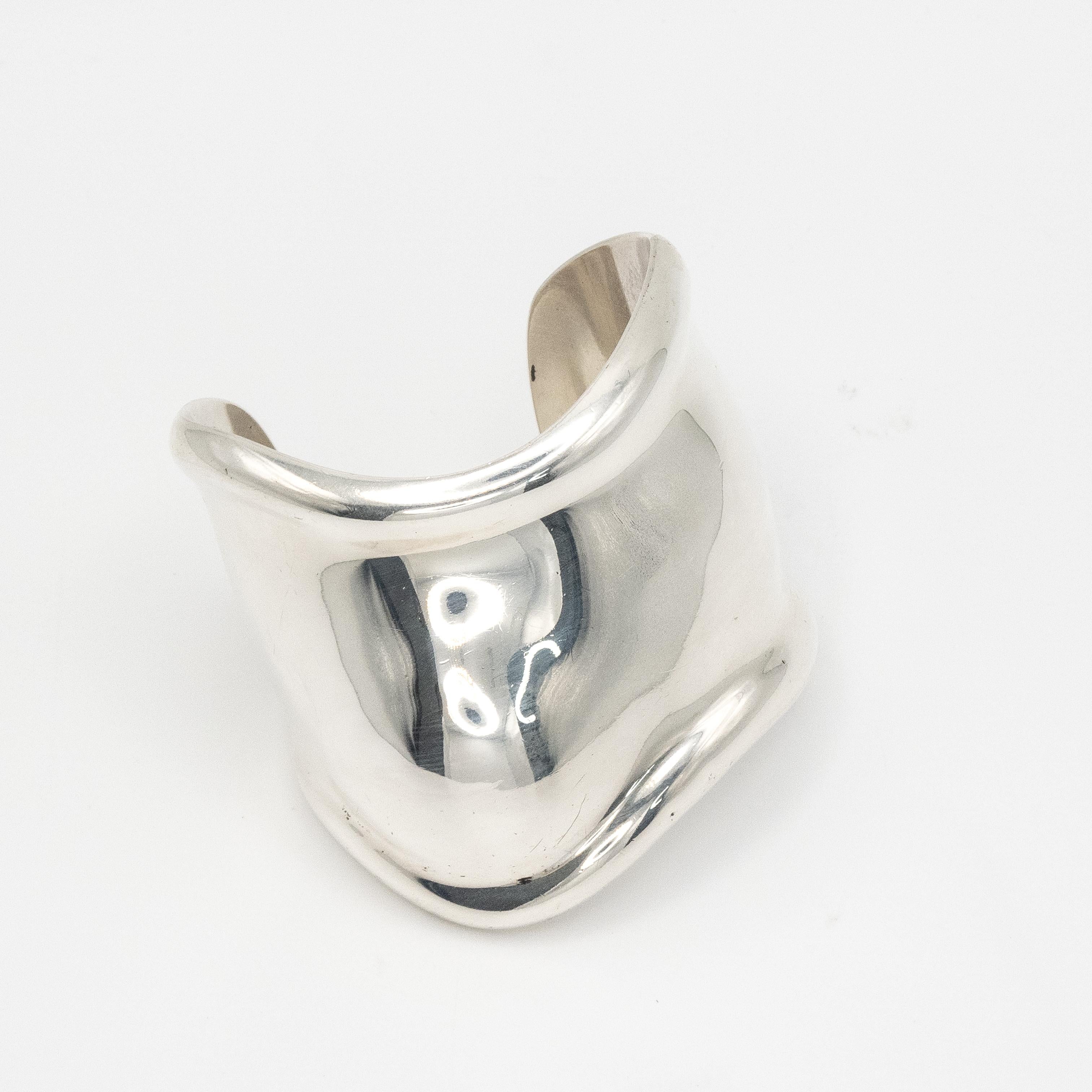 L'emblème de Tiffany & Co. Bracelet manchette en os Elsa Peretti (main droite)  en argent 925 fabriqué en Italie. Doté de la forme sculpturale et organique caractéristique de Peretti, ce modèle audacieux et fluide épouse élégamment les contours du