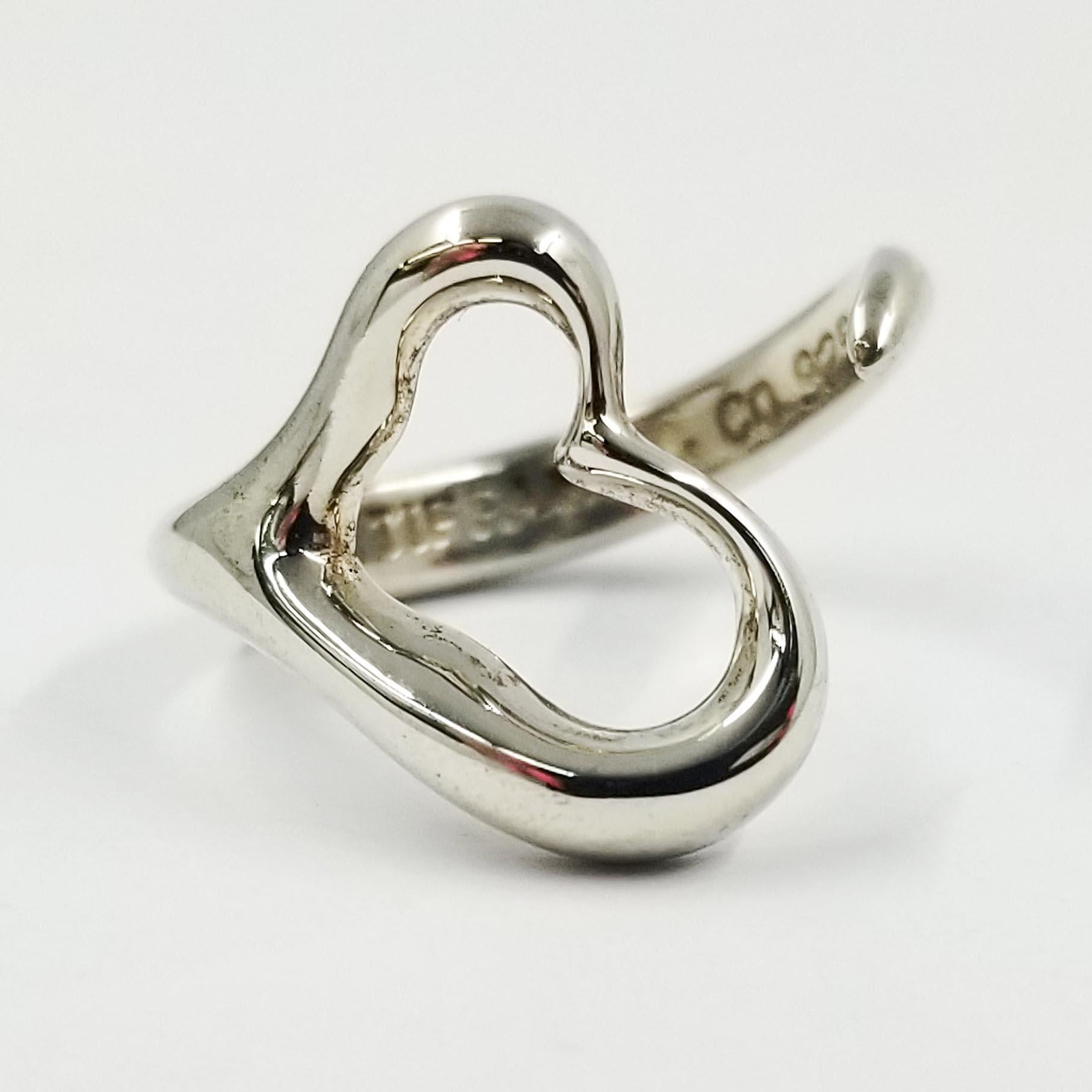 This simple sterling silver ring is designed by Elsa Peretti for Tiffany & Co. Its whimsical design features a heart with wrap around open shank. The inside is engraved with Elsa Peretti's signature, TIFFANY & CO., & 925. Currently finger size 6;
