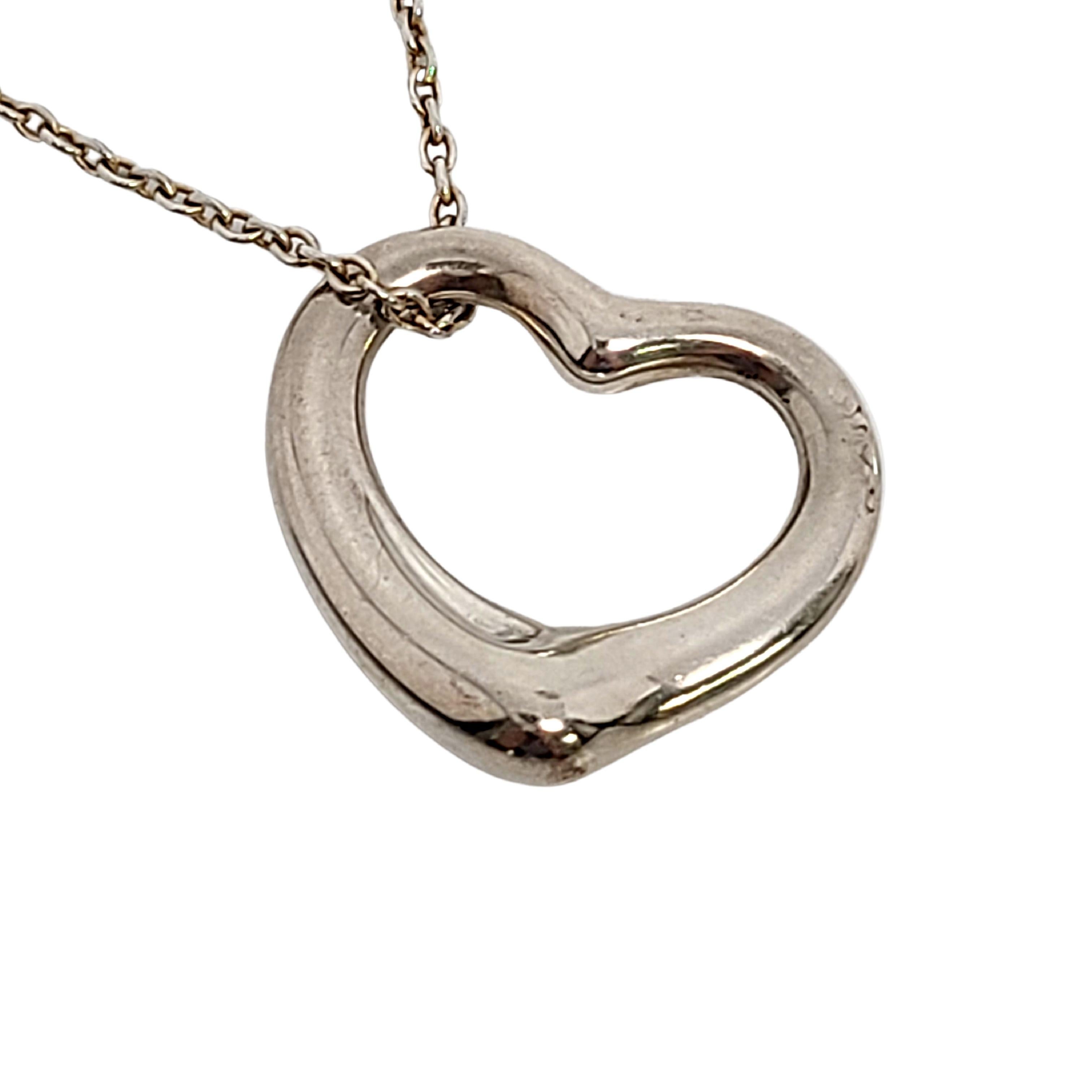 Tiffany & Co sterling silver Open Heart pendant with chain by Elsa Peretti.

An authentic Tiffany & Co necklace featuring a sterling silver pendant in Elsa Peretti's timeless signature open heart design on a delicate chain. Tiffany pouch and box not