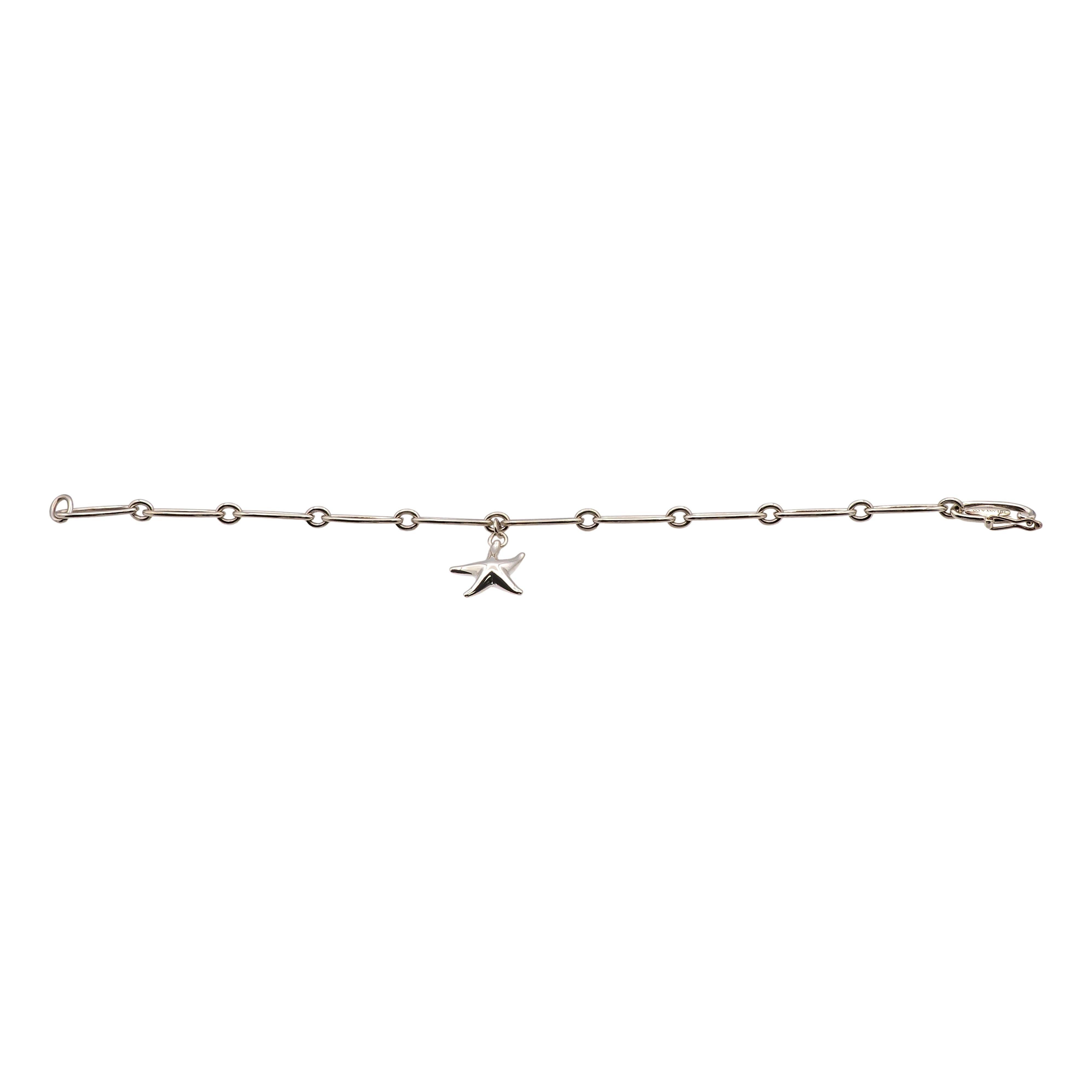 This Tiffany & Co. bracelet, designed by Elsa Peretti, features the iconic starfish motif, crafted in sterling silver. The delicate yet bold design showcases a 15mm starfish charm suspended on a 7.5-inch chain with 5.6mm wide links, secured with a