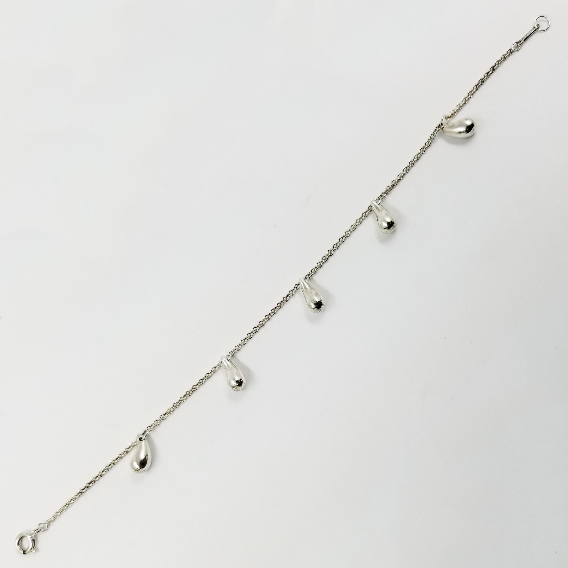 This sterling silver bracelet is crafted by Tiffany & Co. It features 5 tear drop charms throughout its 7.25 inch length. Closure is a spring ring with open ring. Tab near clasp is engraved Peretti T&CO 925. 