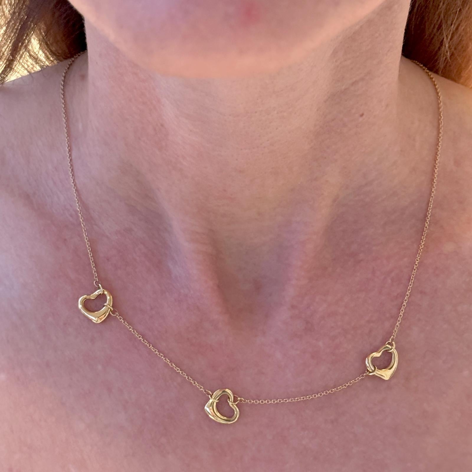 This elegant Tiffany & Co. Elsa Peretti necklace, crafted in 18-karat yellow gold, features the iconic three open-heart pendant design, embodying timeless simplicity and modern elegance. The delicate chain measures 16 inches, perfectly complementing