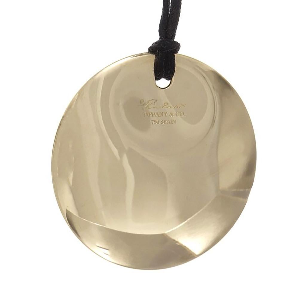 Tiffany & Co Elsa Peretti round pendant in 18k yellow gold on an 18 inch black silk cord. 20 inches in length. 

18k yellow gold
Tested: 18k
Stamped: 750
Hallmark: Tiffany & Co Elsa Peretti Spain
11.7 grams
Top to bottom: 34.46mm or 1.36