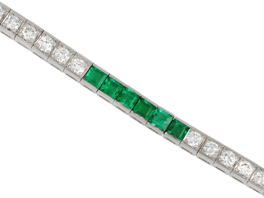 Tiffany & Co. emerald and diamond line bracelet. Set with twenty four square step cut natural emeralds in open back half rubover settings with a combined approximate weight of 3.60 carats, further set intermittently with twenty eight round