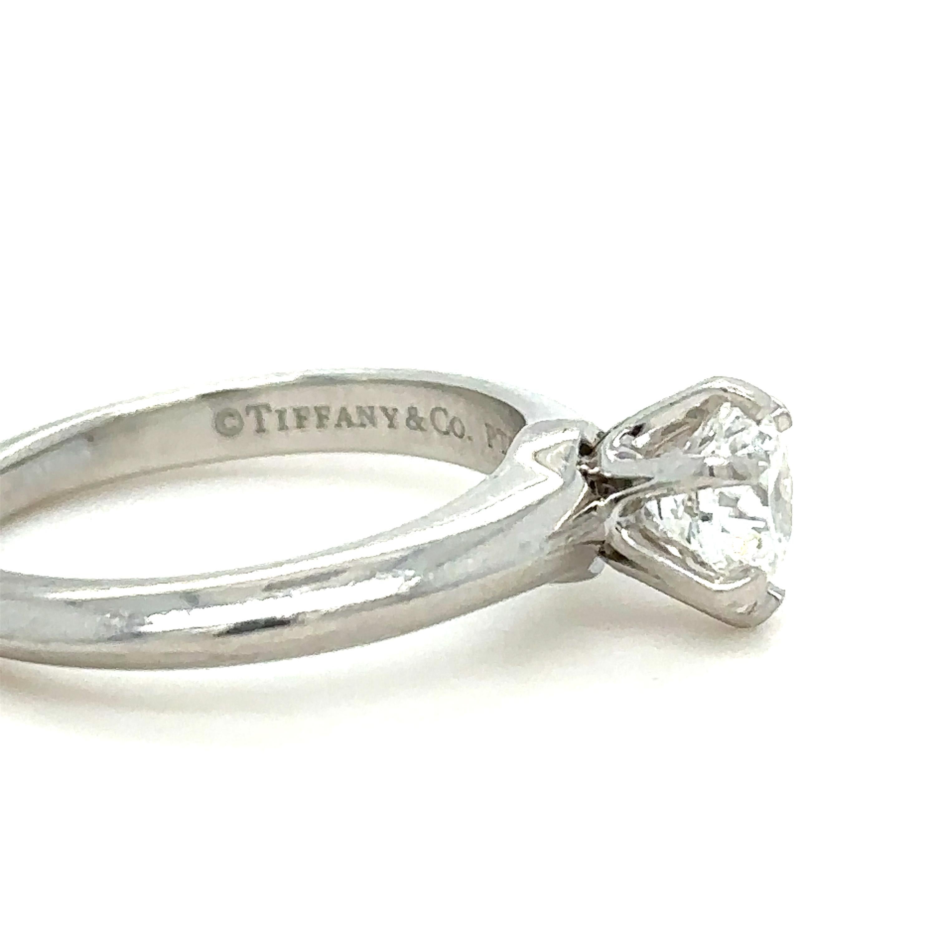 Une bague solitaire en platine et diamant de Tiffany & Co., sertie d'un diamant rond de taille brillant pesant 0,94 carat, couleur F, pureté VVSI.

Métal : Platine PT950
Carat : 0.94ct
Couleur : F
Clarté : VVS1
Coupe : Solitaire
Poids :