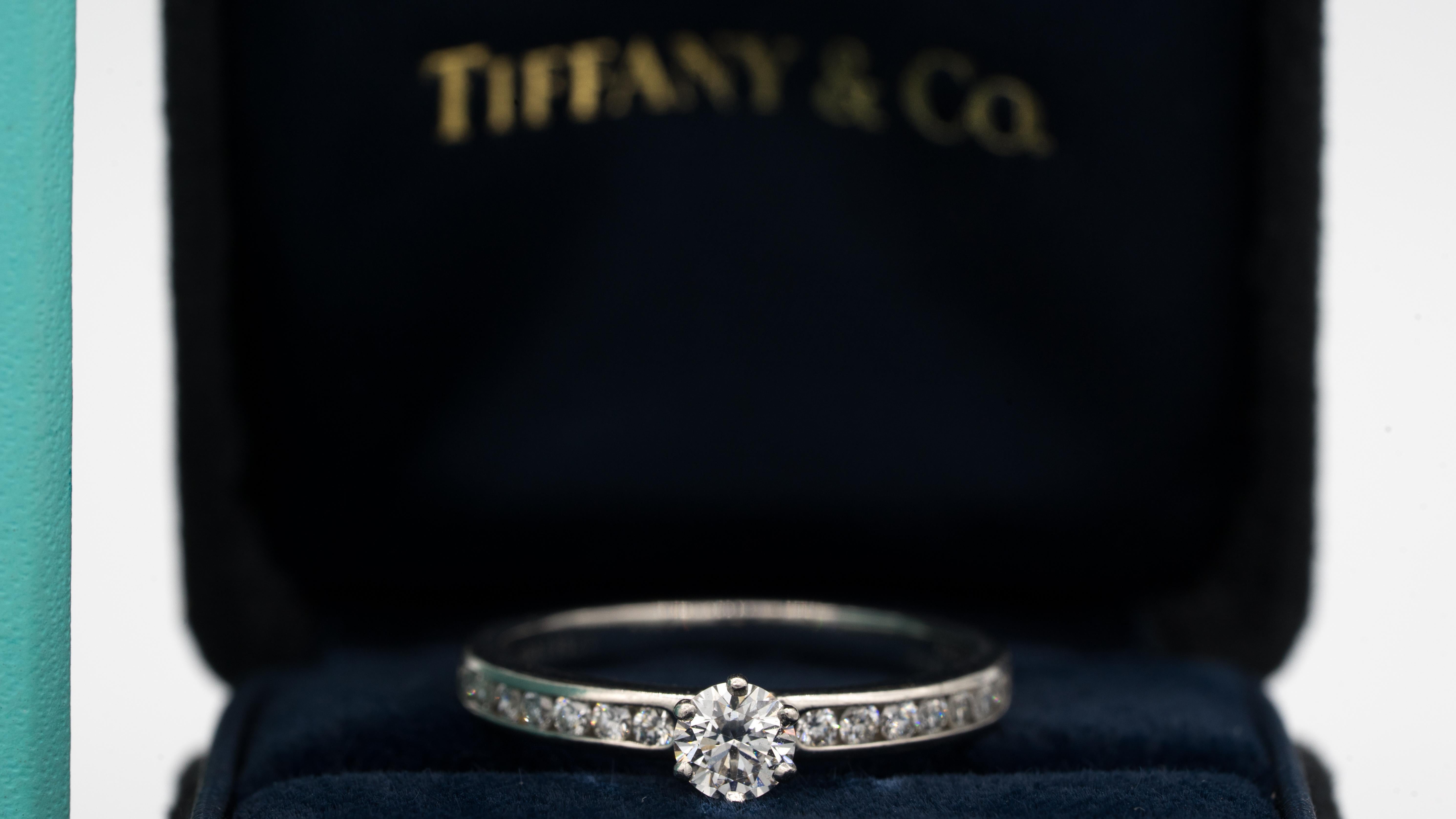 Tiffany & Co. Diamond Engagement Ring with Channel Set Diamond band signed by Tiffany & Co. featuring a .30 ct Center, graded by Tiffany G color , and VVS2 Clarity In Platinum.  Center diamond is flanked on each side by 7 diamonds , for a total of