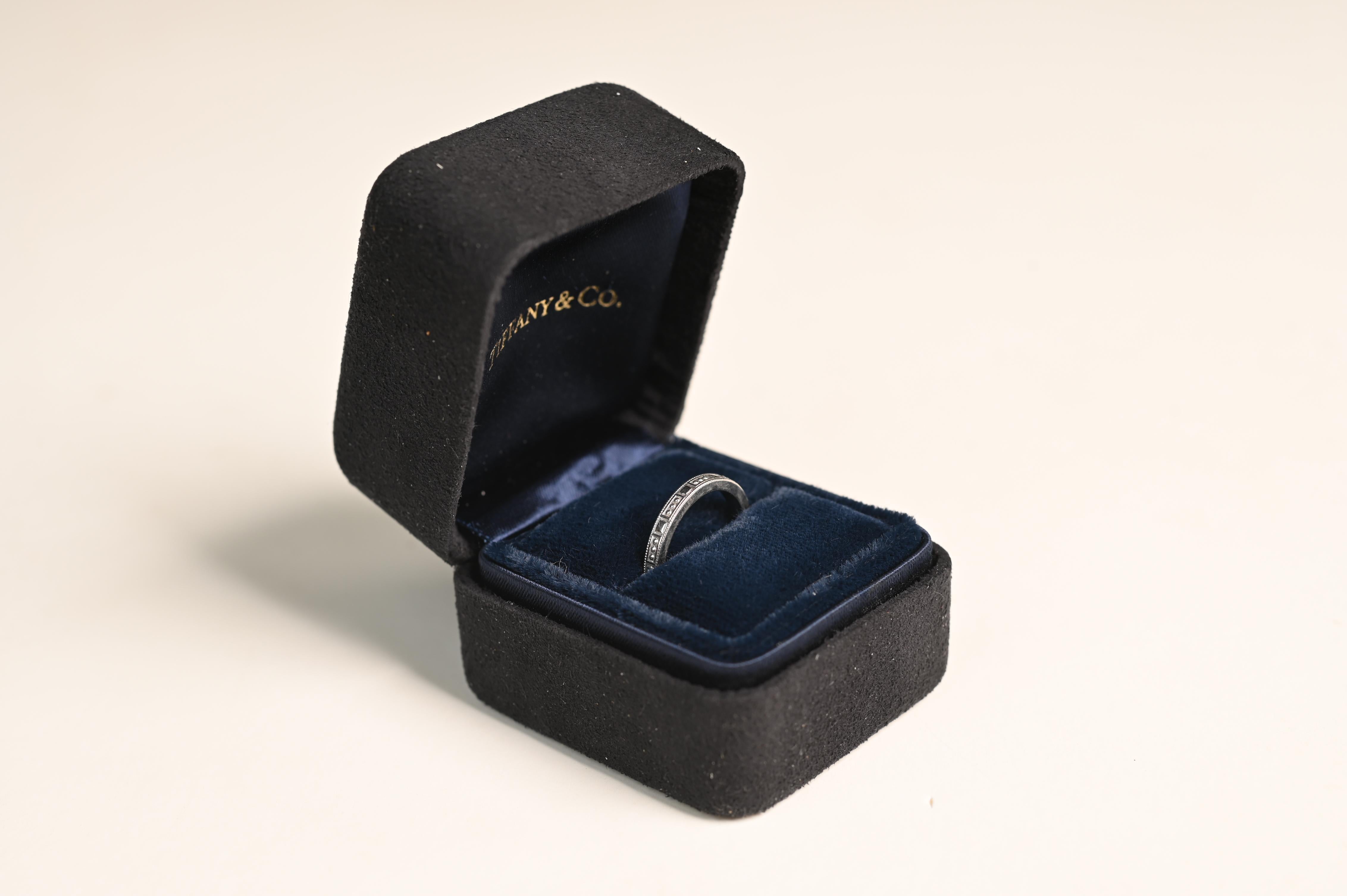 Cette exquise alliance en platine de Tiffany & Co. est une démonstration magistrale d'élégance intemporelle et de savoir-faire supérieur. Doté d'un motif gravé complexe qui s'étend de manière harmonieuse sur toute la circonférence, ce bracelet