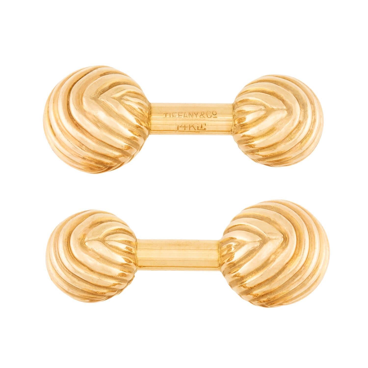 Ein zeitloses Paar Manschettenknöpfe vom legendären Designer Tiffany & Co! Jeder Manschettenknopf ist aus 14 Karat Gelbgold gefertigt und mit zwei kleinen Goldkugeln versehen. Obwohl die Kugeln in ihrer Größe leicht variieren, ist die Oberfläche