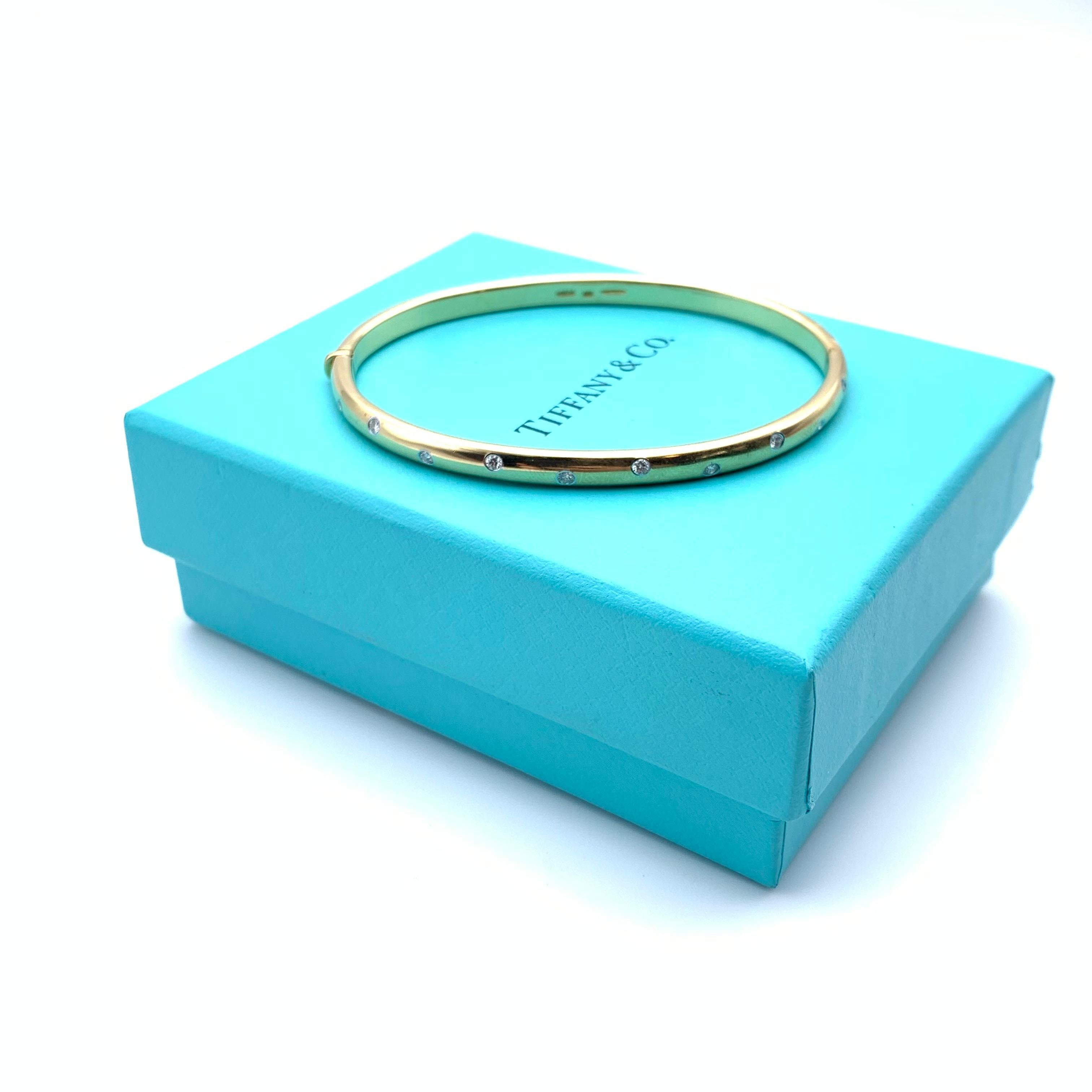 This classic station design from Tiffany & Co. is a favorite from the 1990's. It is made of 18-karat yellow gold with platinum accents around the diamond settings. The bangle is flush set with 0.22 carats of round, full-cut diamonds. The melee grade