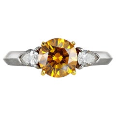 Tiffany & Co Fancy deep orange-yellow diamond flanked solitaire ring, American.