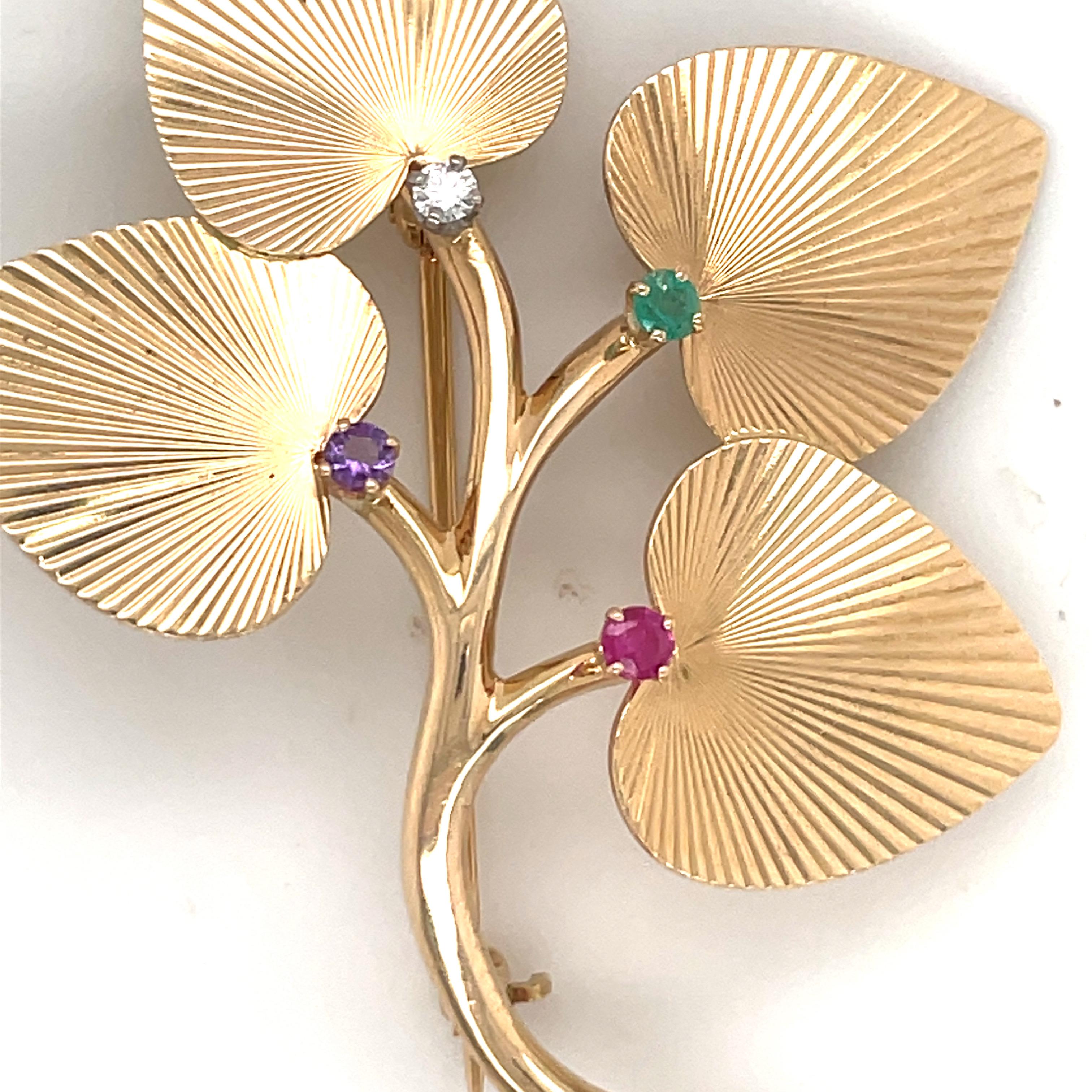 Estampillée Tiffany & Co, cette broche florale ornée d'un diamant, d'une émeraude, d'un rubis et d'une améthyste est réalisée en or jaune 14 carats.
Boucles d'oreilles assorties. 