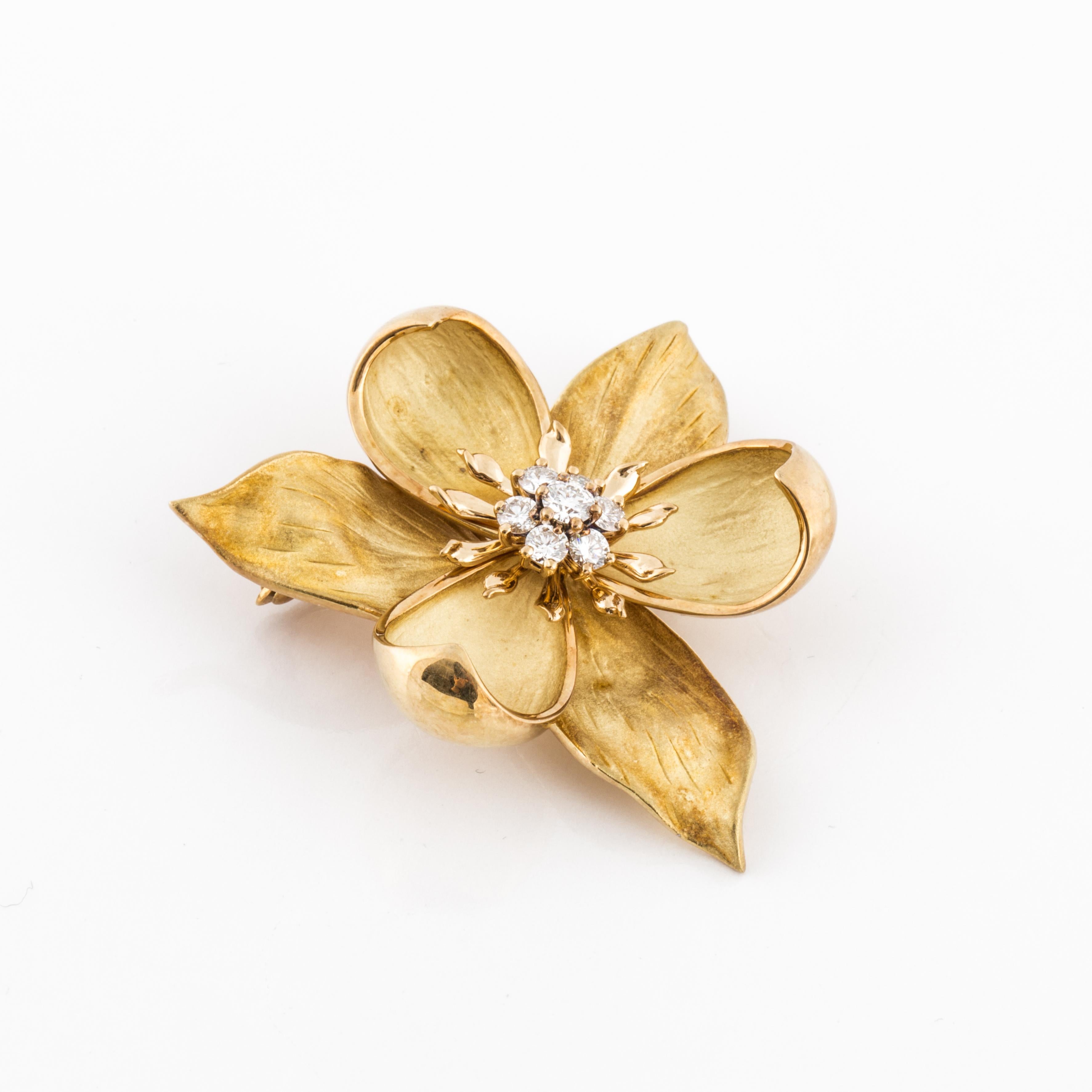 Tiffany & Co. flower pin in 18K yellow gold accented by round diamonds.  There are seven round brilliant-cut diamonds that total 0.70 carats; F-G color and VVS2-VS1 clarity.  It measures 1 3/4 inches long and 1 3/4 inches wide.  