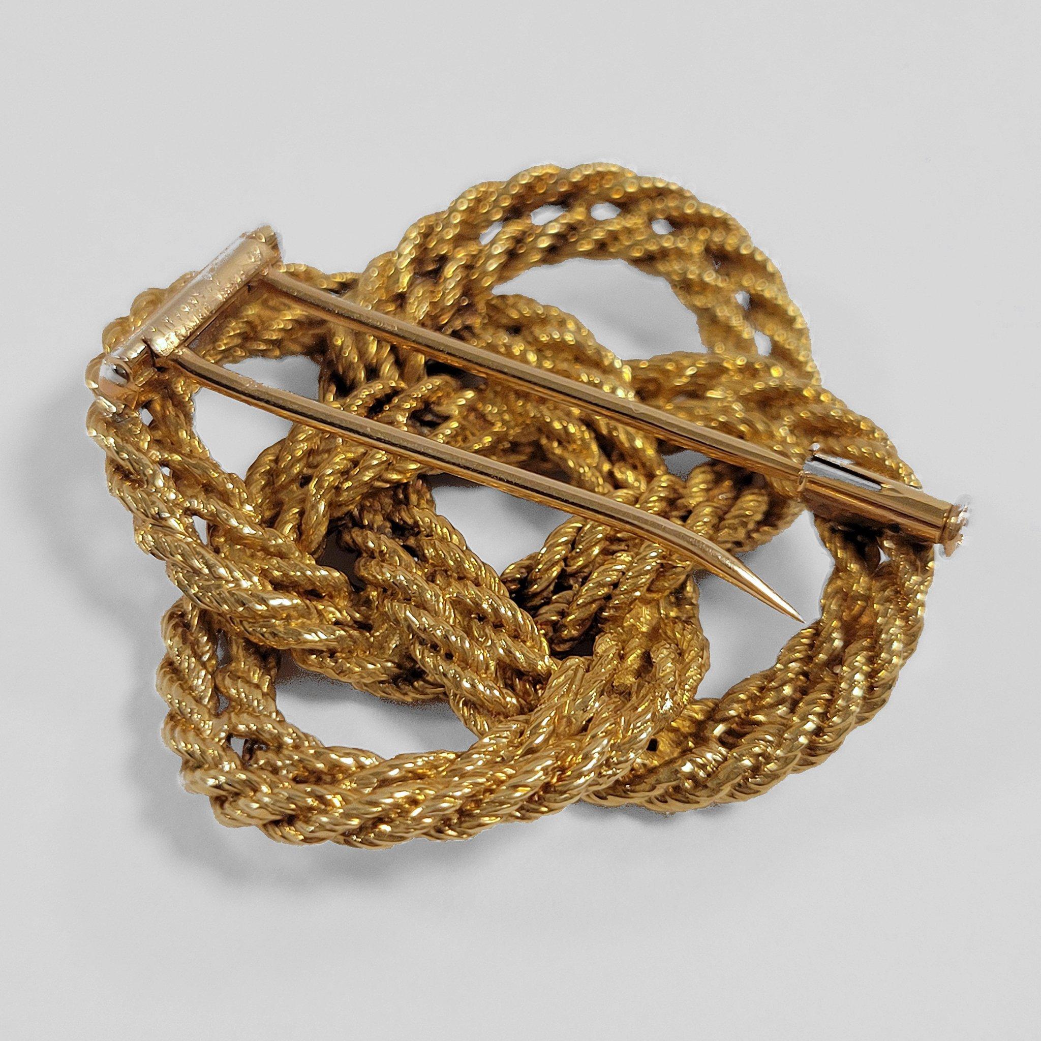 Made in the 1960s, this gold knot brooch was created by Tiffany & Co. Composed of  a double strand of gold rope twist, the brooch is designed as a square knot motif of eight crossings. A classic Tiffany & Co. form of the 1960s, this classic bold