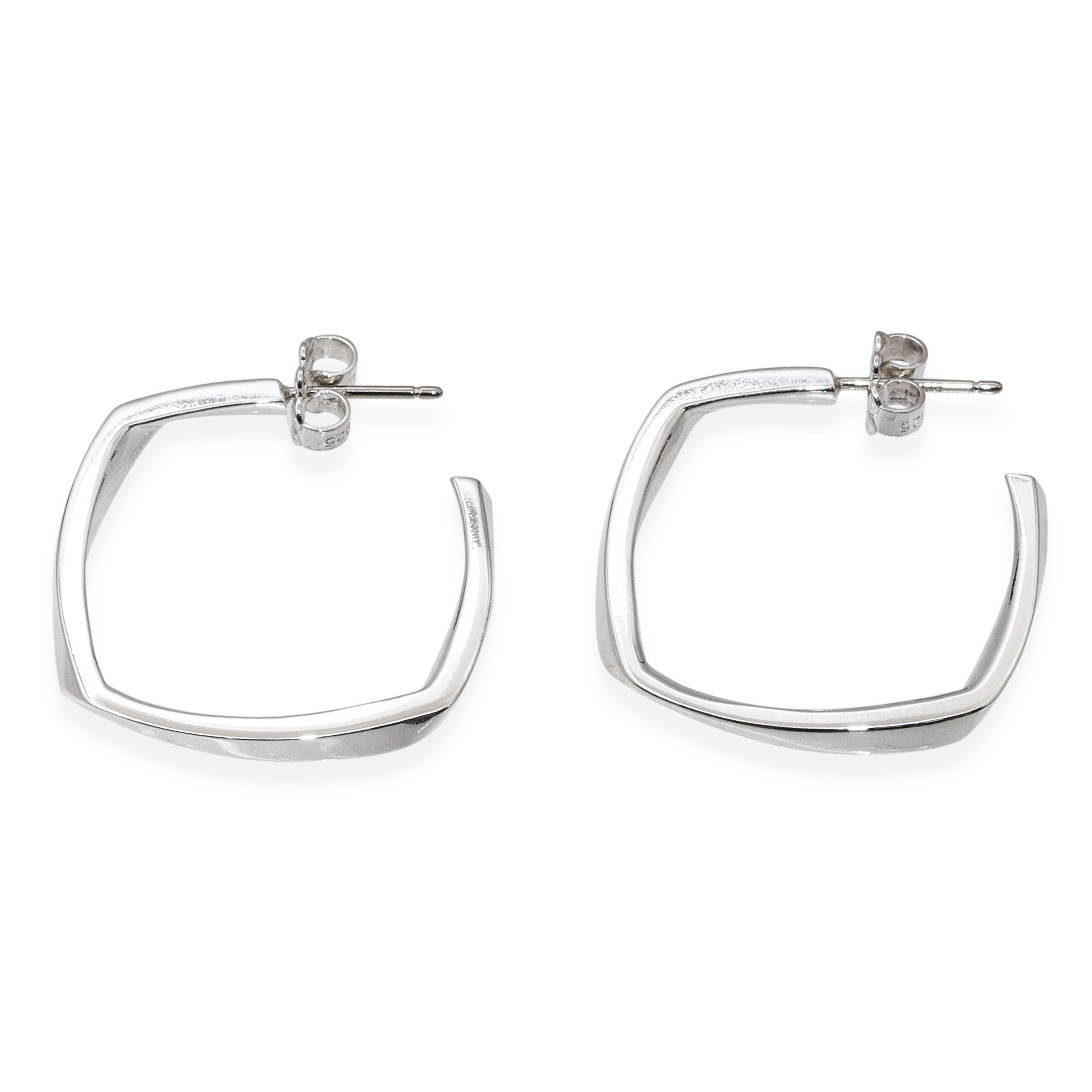 Designed by Frank Gehry for Tiffany & Co., these earrings feature a bold square hoop silhouette with a torque design that’s both modern and sculptural. Crafted in polished sterling silver, they balance architectural edge with wearable elegance.