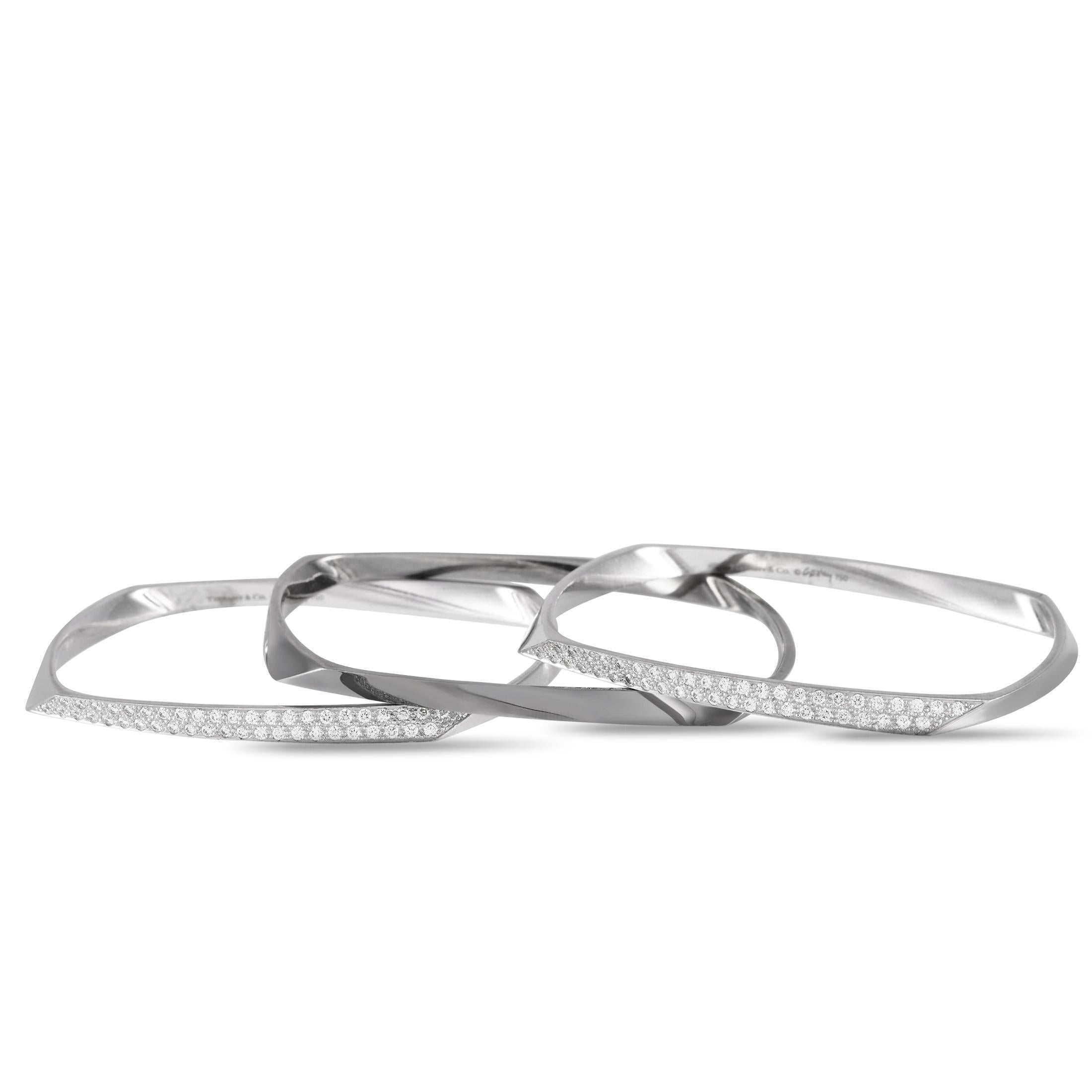 This Tiffany & Co. Gehry Bracelet Set features a trio of uniquely elegant 18K White Gold bangle bracelets. Meant to be worn together as a stacked set, each piece features clean lines and a distinctly modern sense of style. Two of the bracelets come