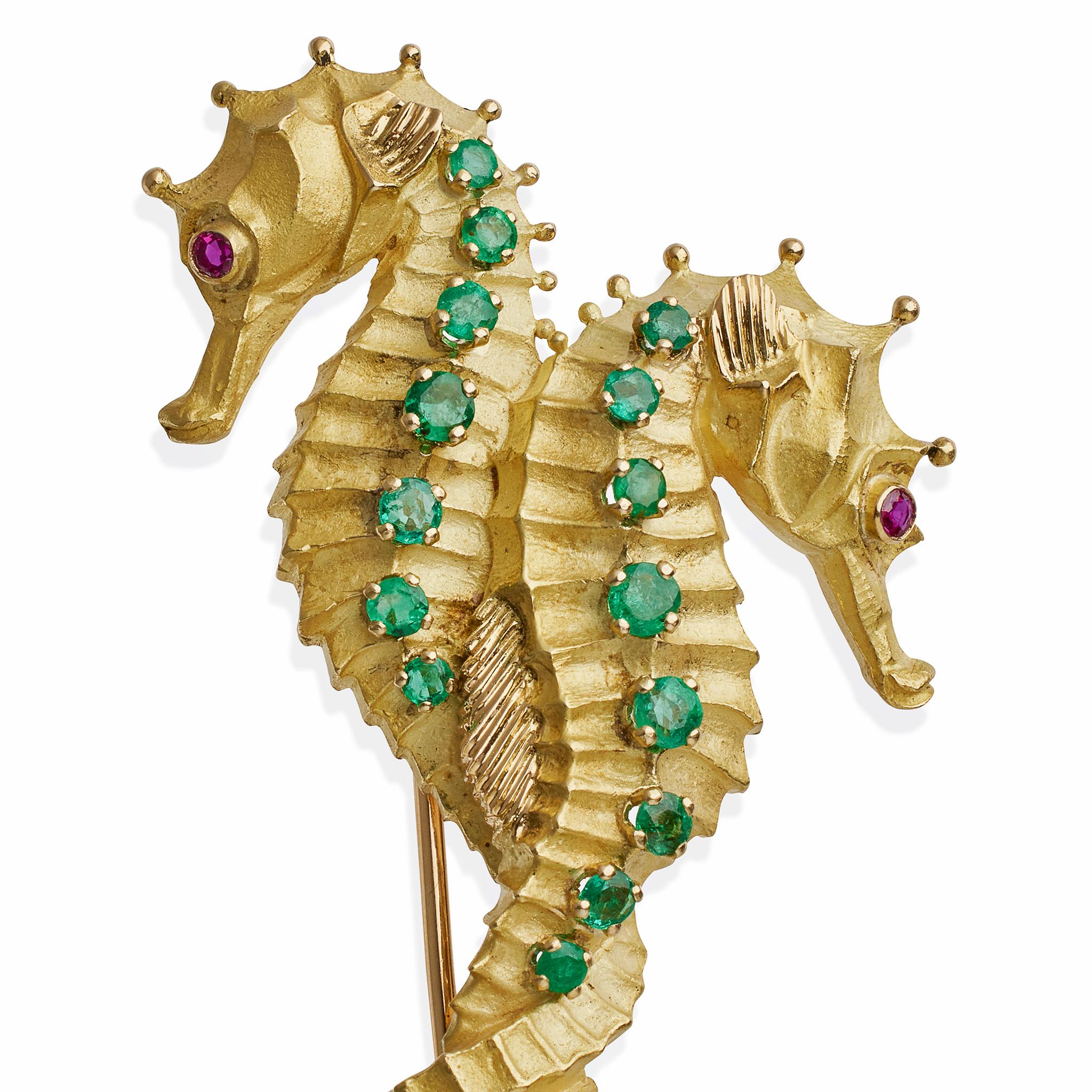Créée à Paris pour Tiffany & Co. par la firme de Geroges Lenfant dans les années 1960-1970, cette broche à clip à double hippocampe est composée d'or 18 carats, d'émeraudes et de rubis. Conçus comme des hippocampes aux queues entrelacées, leurs